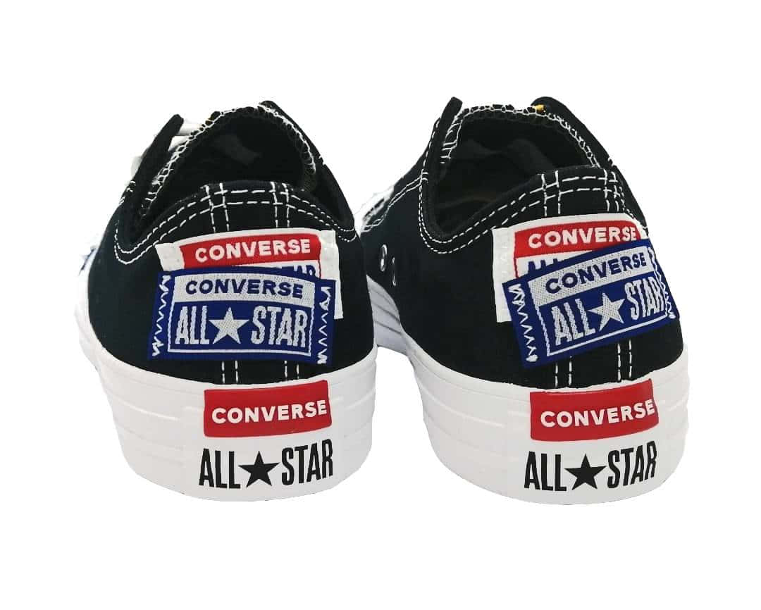 全天候穿著匡威鞋，時尚又舒適 壁紙 — 一對黑色Converse All Star運動鞋從後面看，顯示白色鞋底上堆疊的品牌標誌，背景為乾淨的白色。