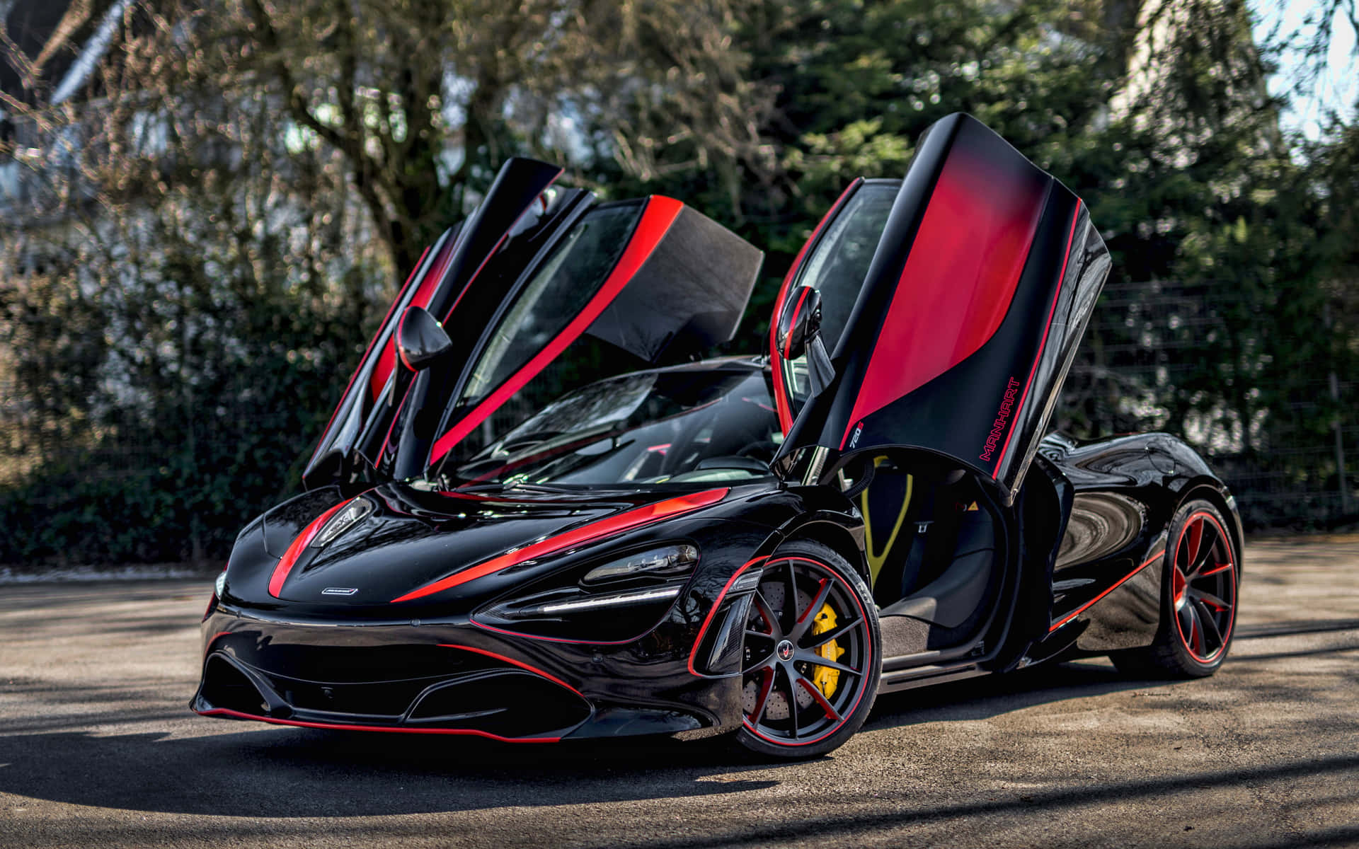 黑色McLaren跑車，帶有紅色點綴和打開的車門，停泊在戶外。