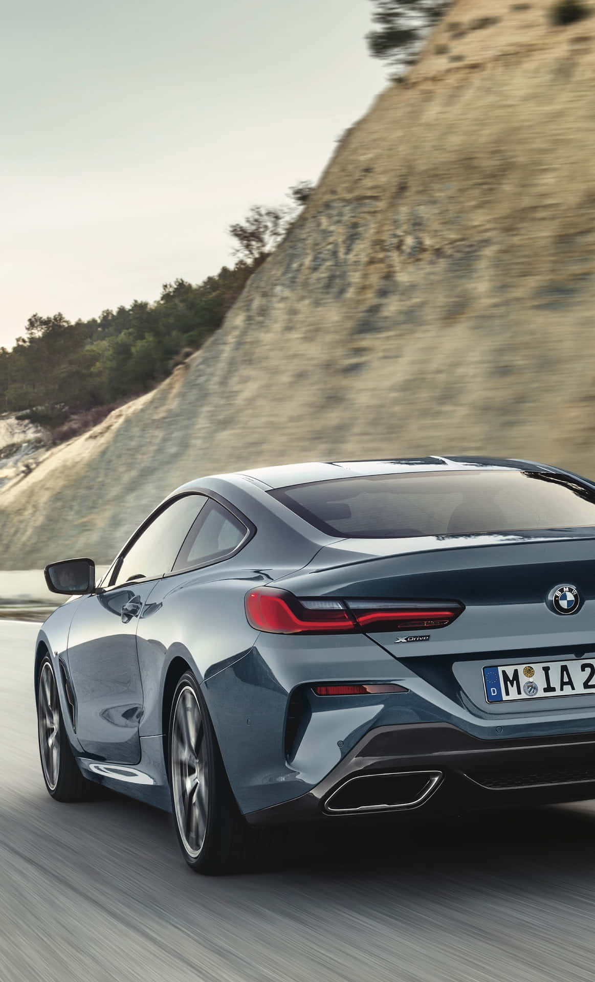 藍色BMW 8系轎跑車在日落時分的山路上奔馳