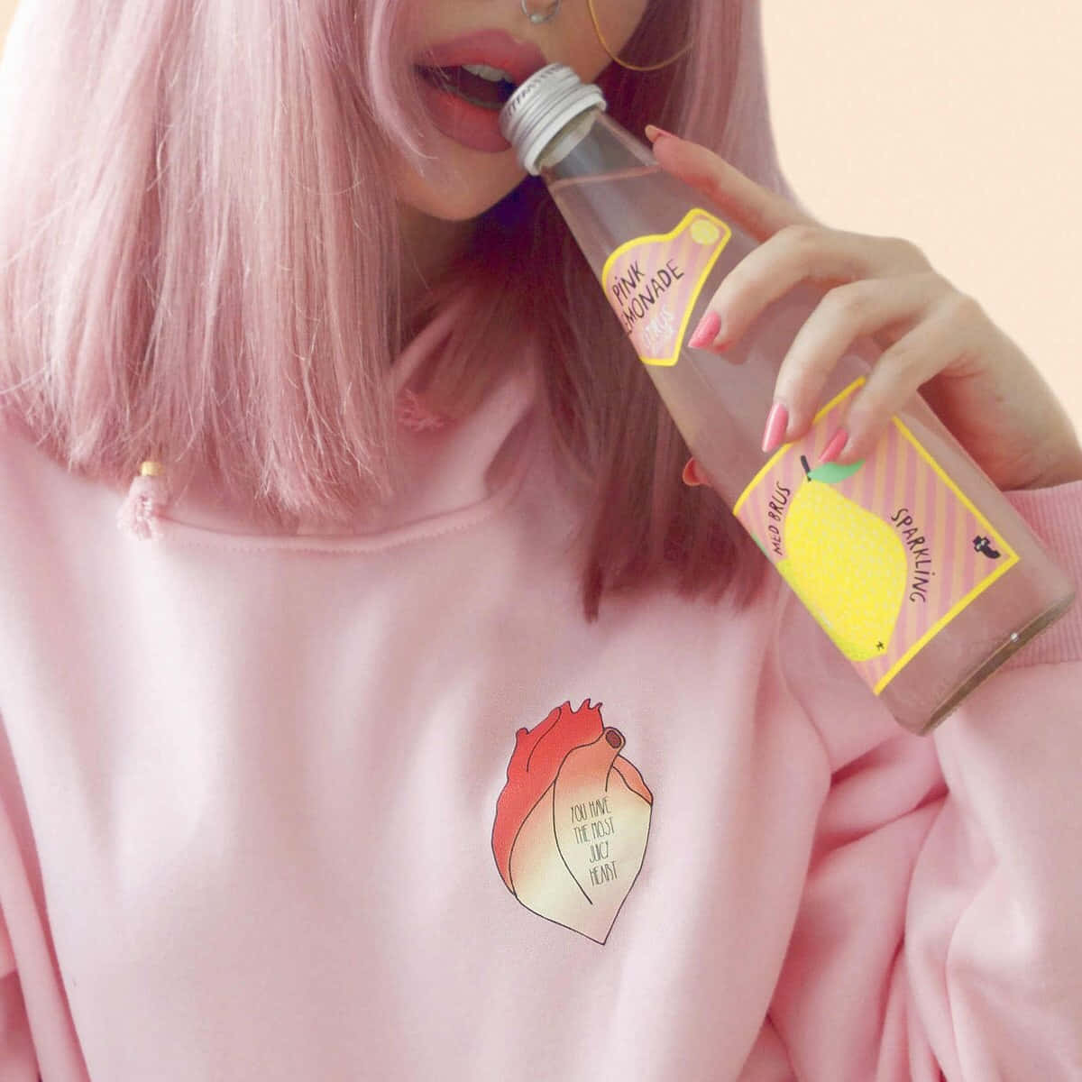 全身粉紅元素女孩頭像 壁紙 — 一位粉紅色頭髮的人士，穿著帶有桃子圖案的粉紅色連帽衫，從玻璃瓶中啜飲粉紅色檸檬水。