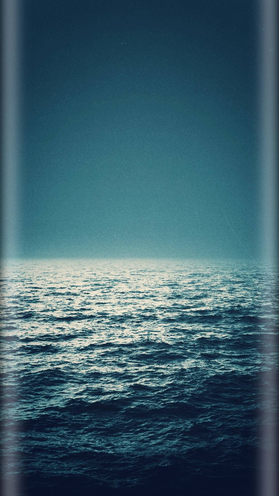 暮色天空下的平靜海洋，溫柔的波浪和垂直框架