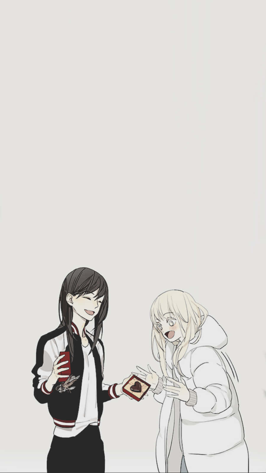 兩位動漫少女共享浪漫時刻 壁紙 — 一個微笑的動漫女孩穿著外套，向一個穿著白色連帽衫的震驚金髮女孩遞上一個心形盒子。