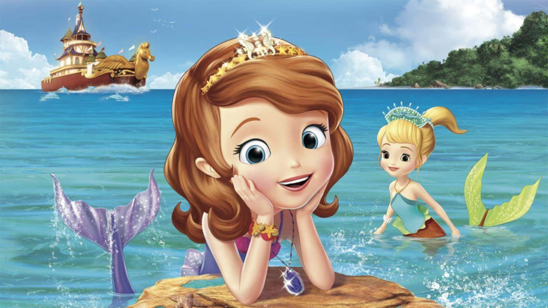 Sofia The First 桌布 壁紙 — 兩位動畫美人魚公主在碧綠的海水中微笑，旁邊是岩石海岸，遠處有一艘幻想船隻航行。