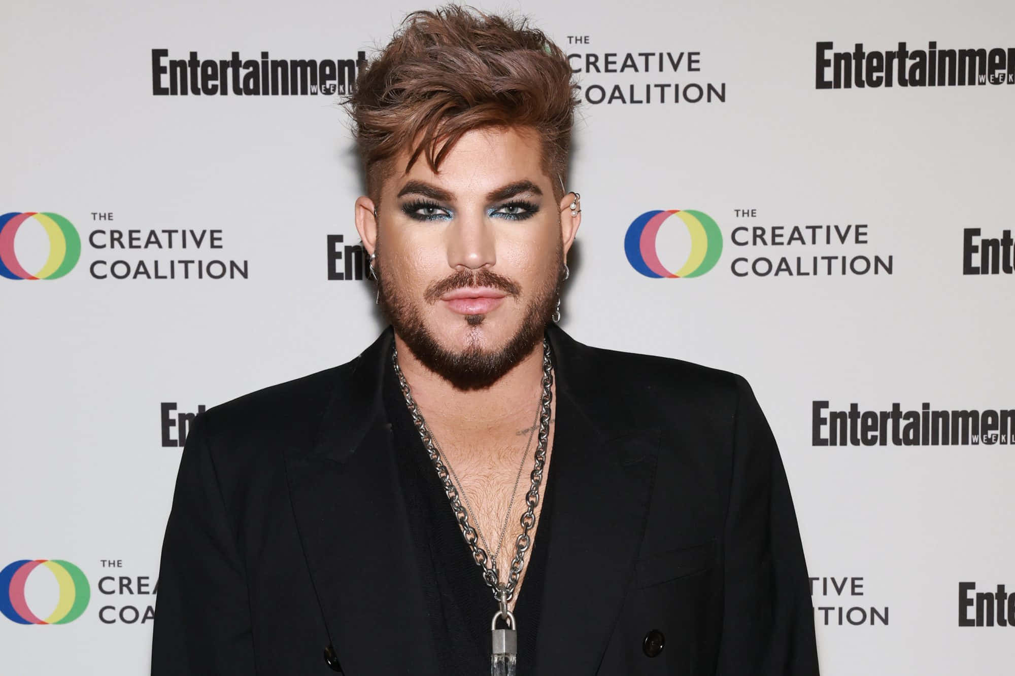 Adam Lambert 在活動中穿著黑色西裝，化著大膽的妝容。