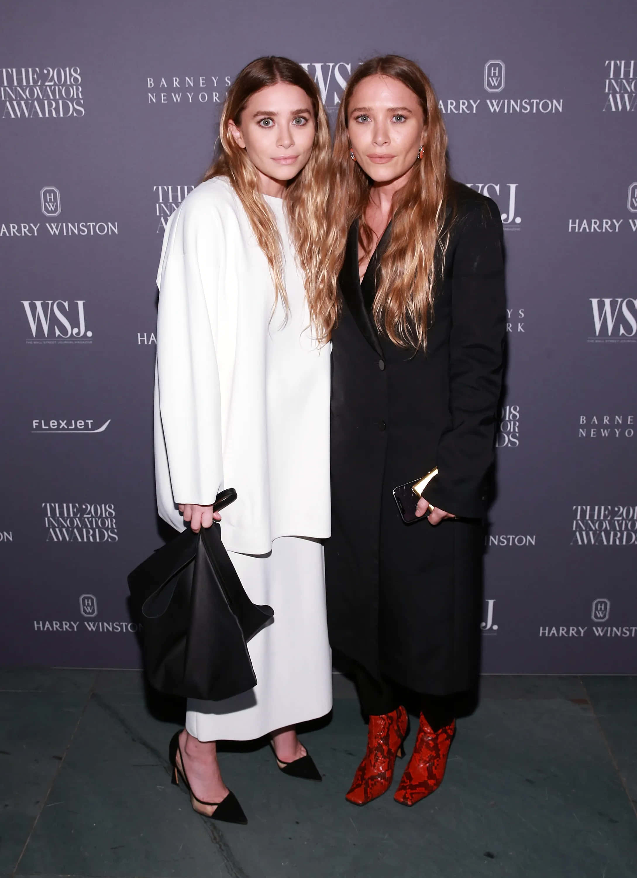 ashley olsen 桌布 壁紙 — 兩位女士在一個正式活動中，於帶有標誌和文字的宣傳背景前優雅地擺姿勢。