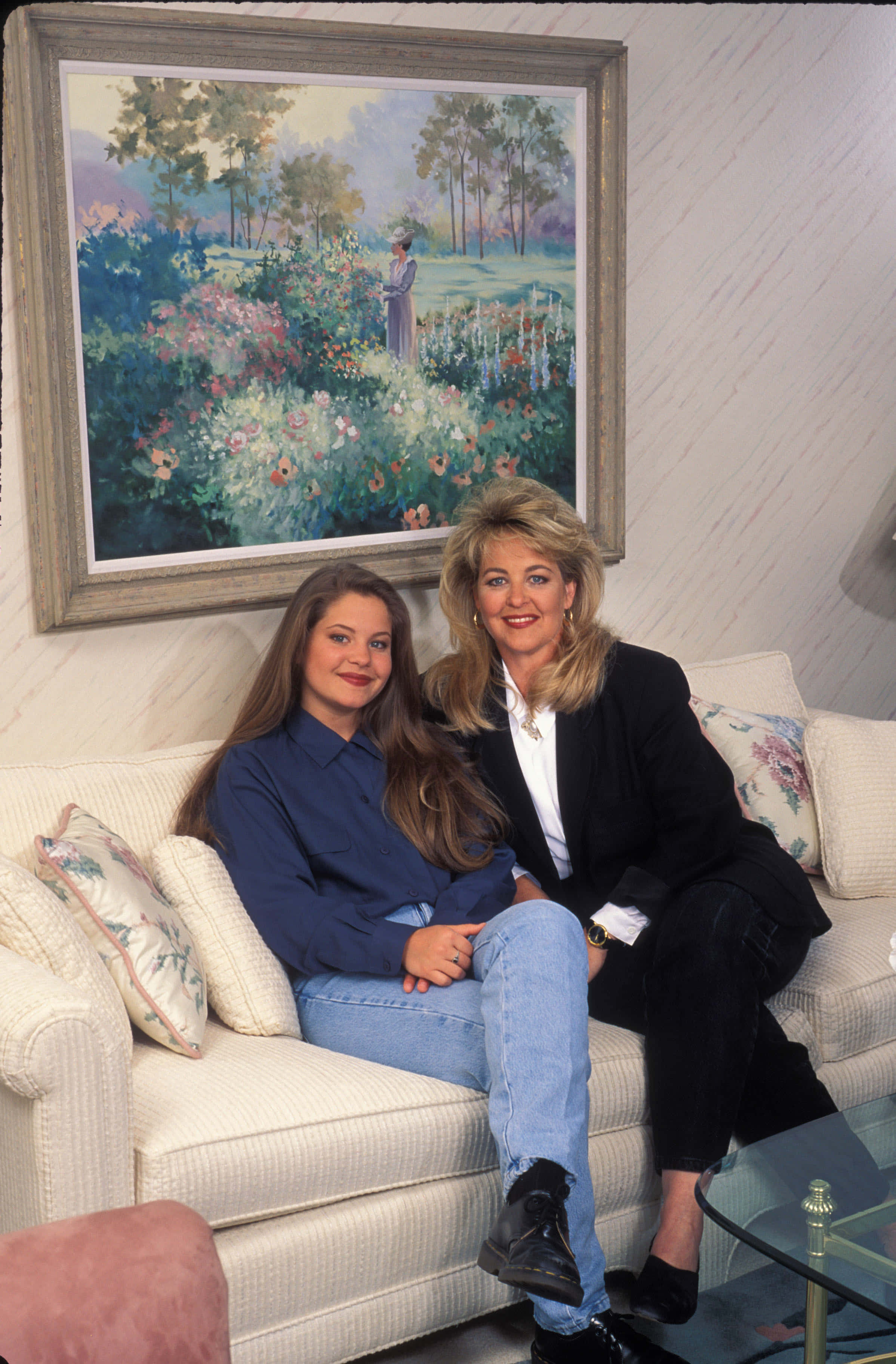 candace cameron bure 桌布 壁紙 — 兩位女士坐在奶油色梳化上，在大型裱框花園花卉畫作下微笑。