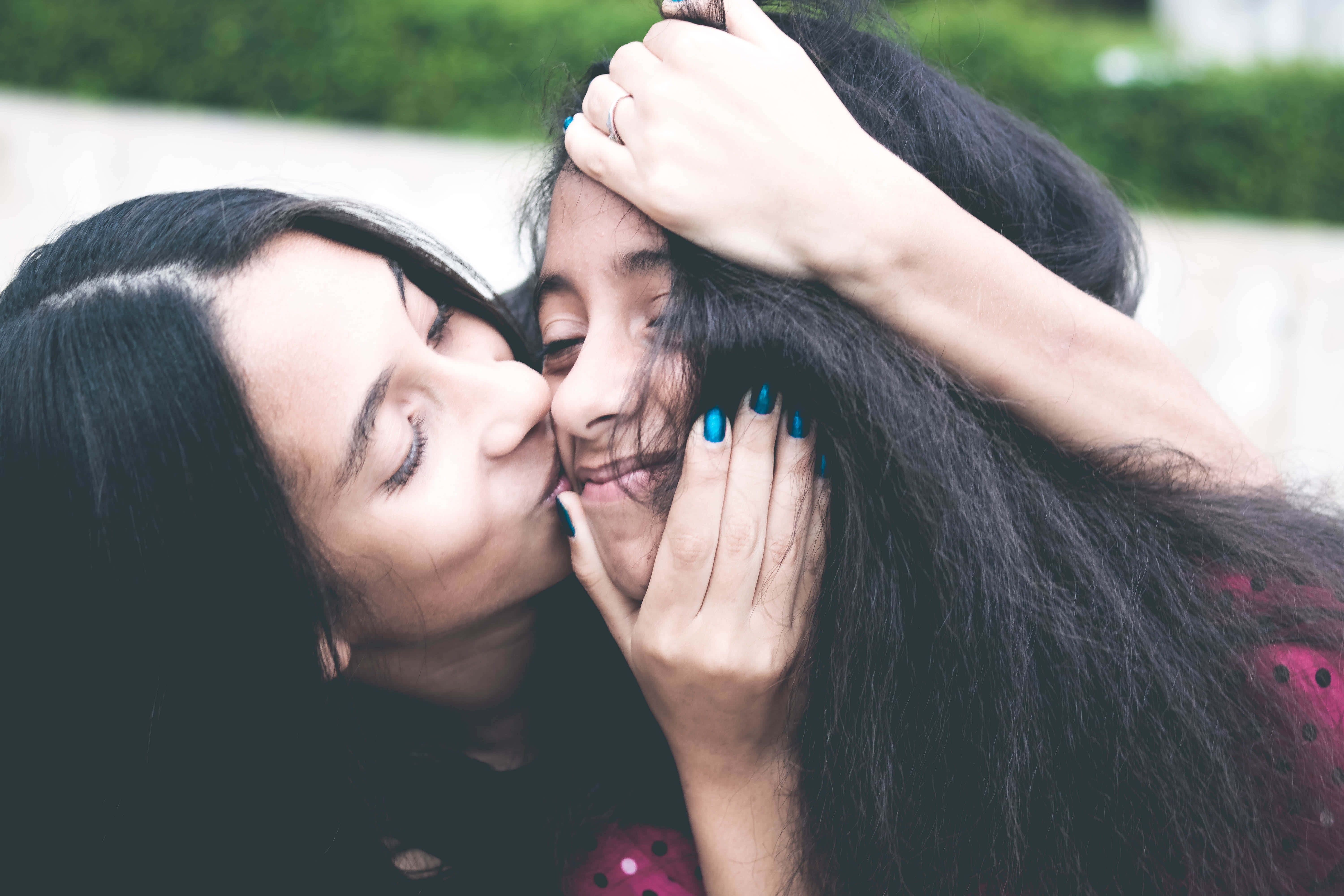 Mom 桌布 壁紙 — 兩位女性分享親密時刻，其中一位輕吻另一位臉頰，同時溫柔地捧著她的臉。