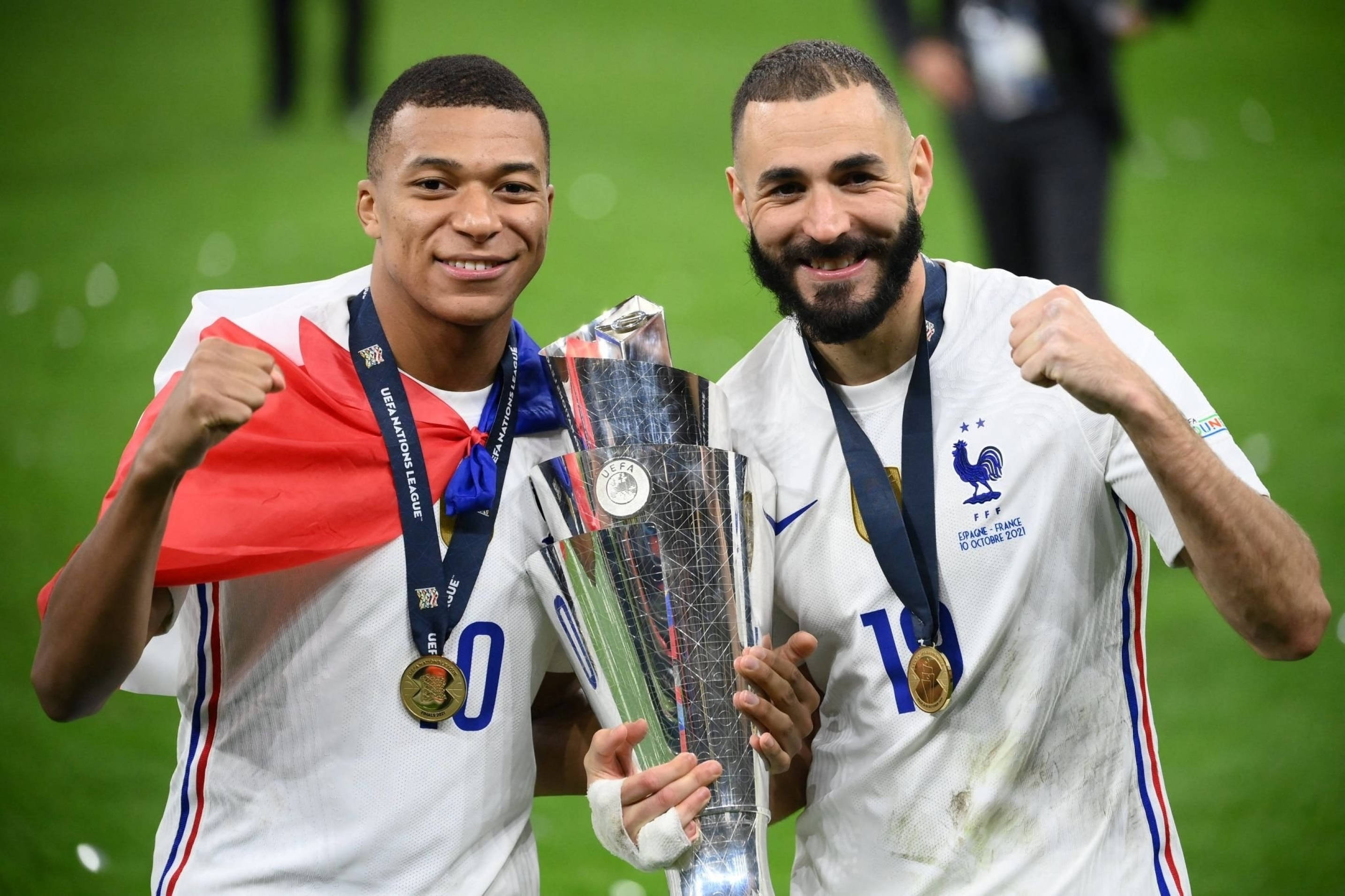 Football Players 桌布 壁紙 — 兩位歡欣的法國足球員舉著閃閃發光的獎盃慶祝勝利，法國國旗披在肩上。
