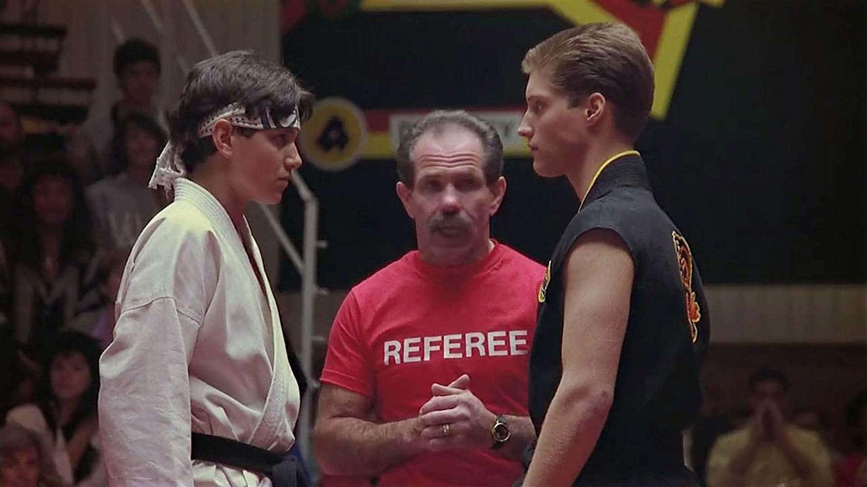 Ralph Macchio 桌布 壁紙 — 兩位武術家在裁判的注視下，在緊張的室內比賽場地中對峙。