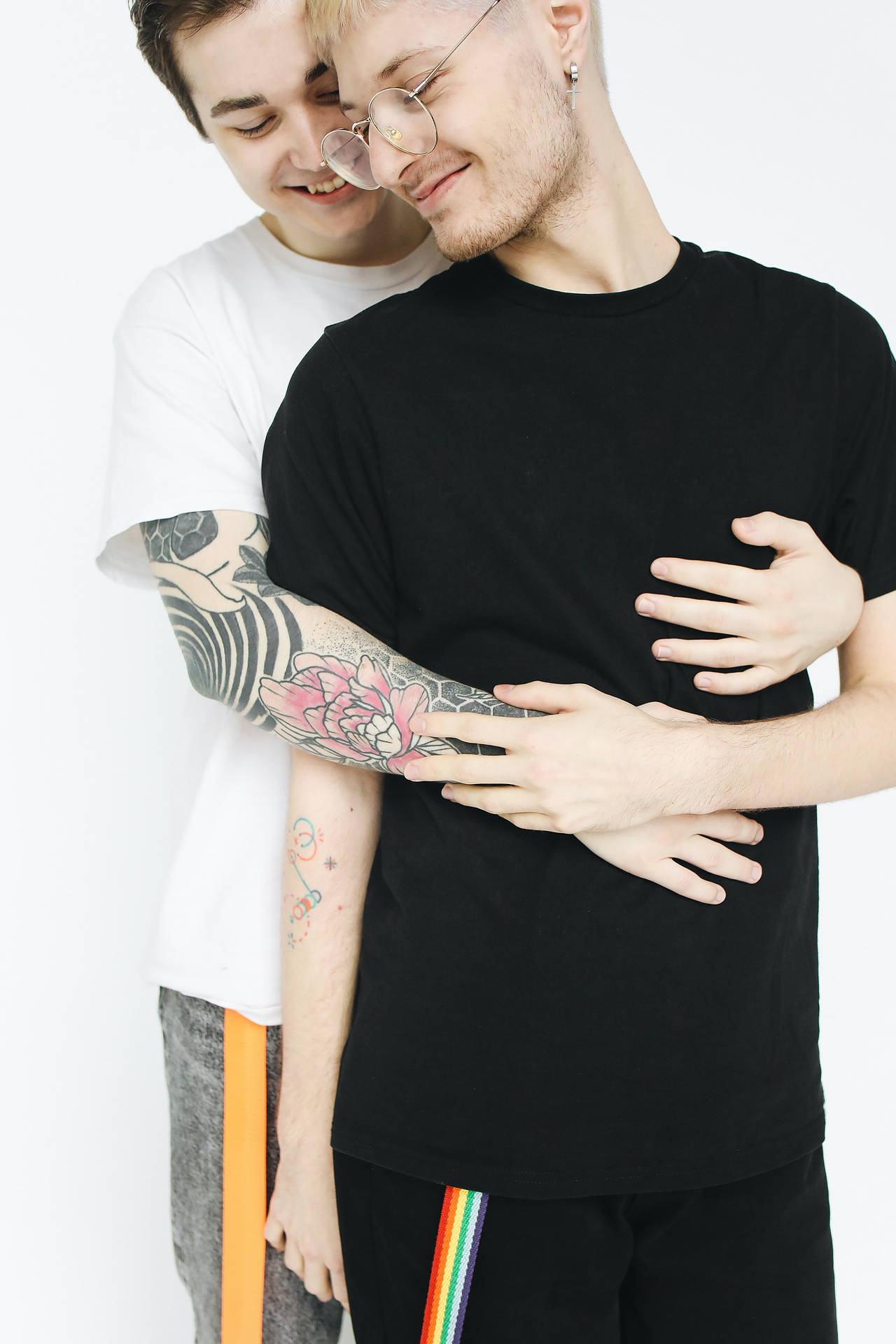 兩個男人擁抱，其中一人有色彩繽紛的紋身手臂。