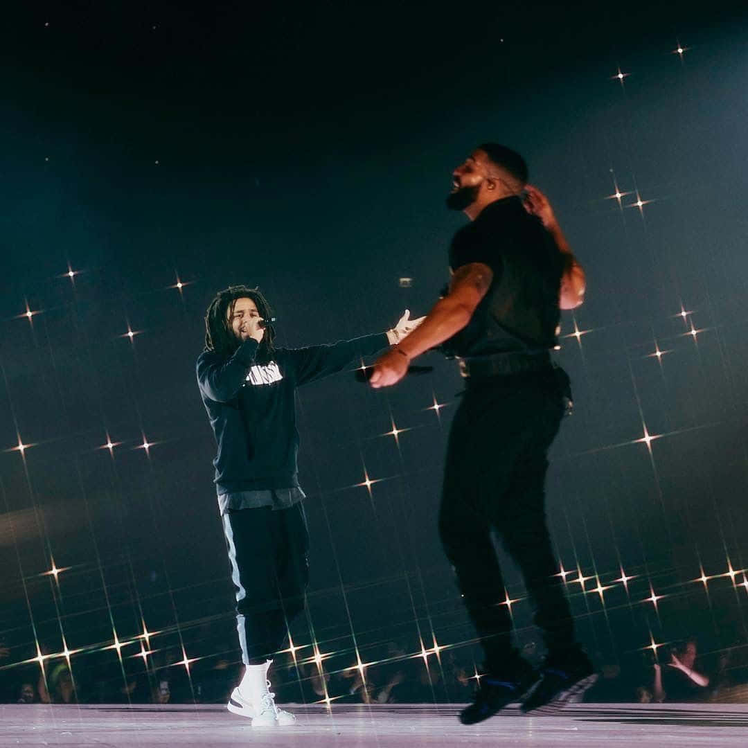 Drake 桌布 壁紙 — 兩位說唱歌手在演唱會表演期間於星光燈光下在舞台上牽手。