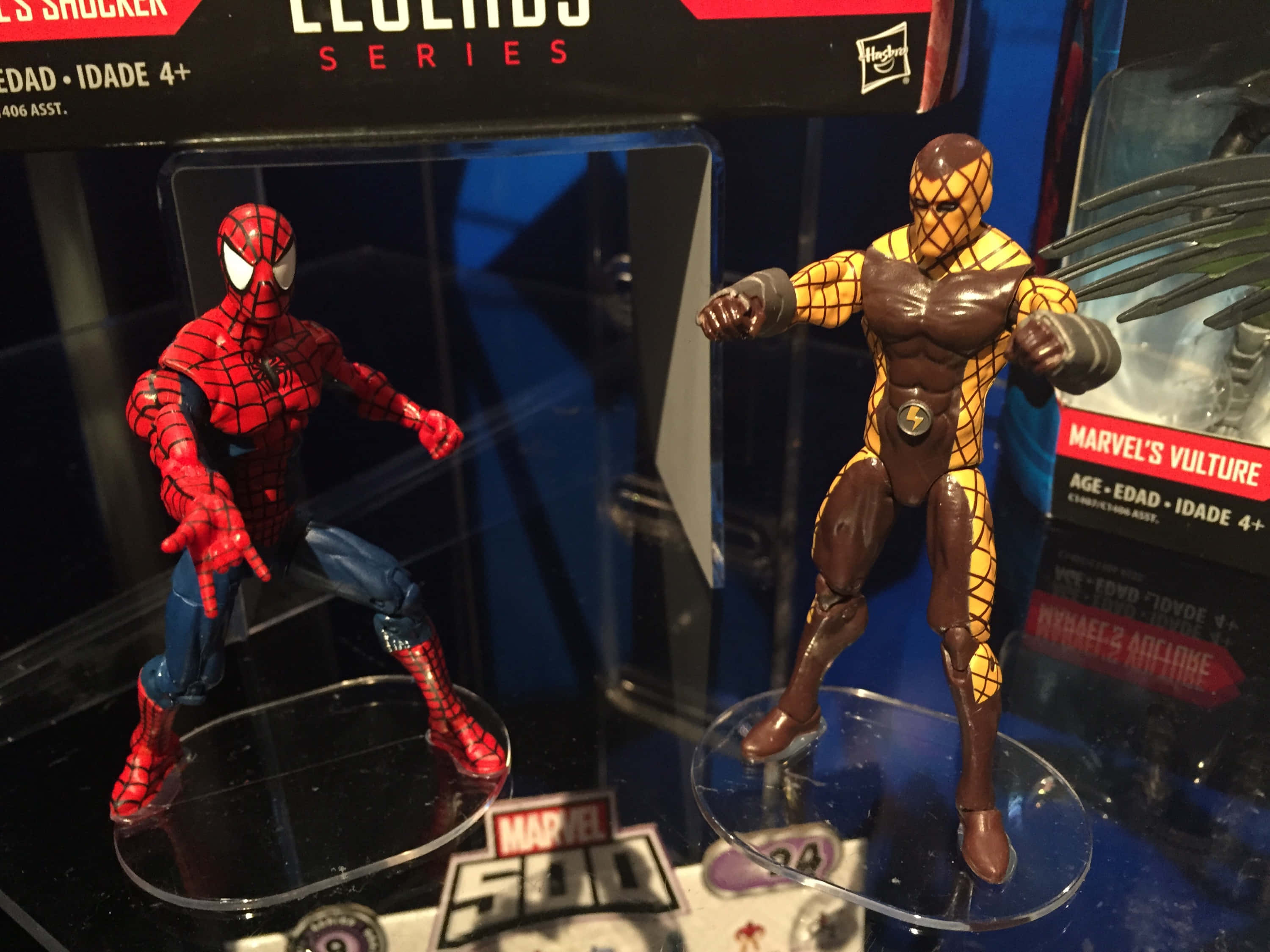 The Shocker 桌布 壁紙 — 兩個Marvel動作人偶蜘蛛俠與禿鷲站在透明底座上，包裝內品牌標識清晰可見。