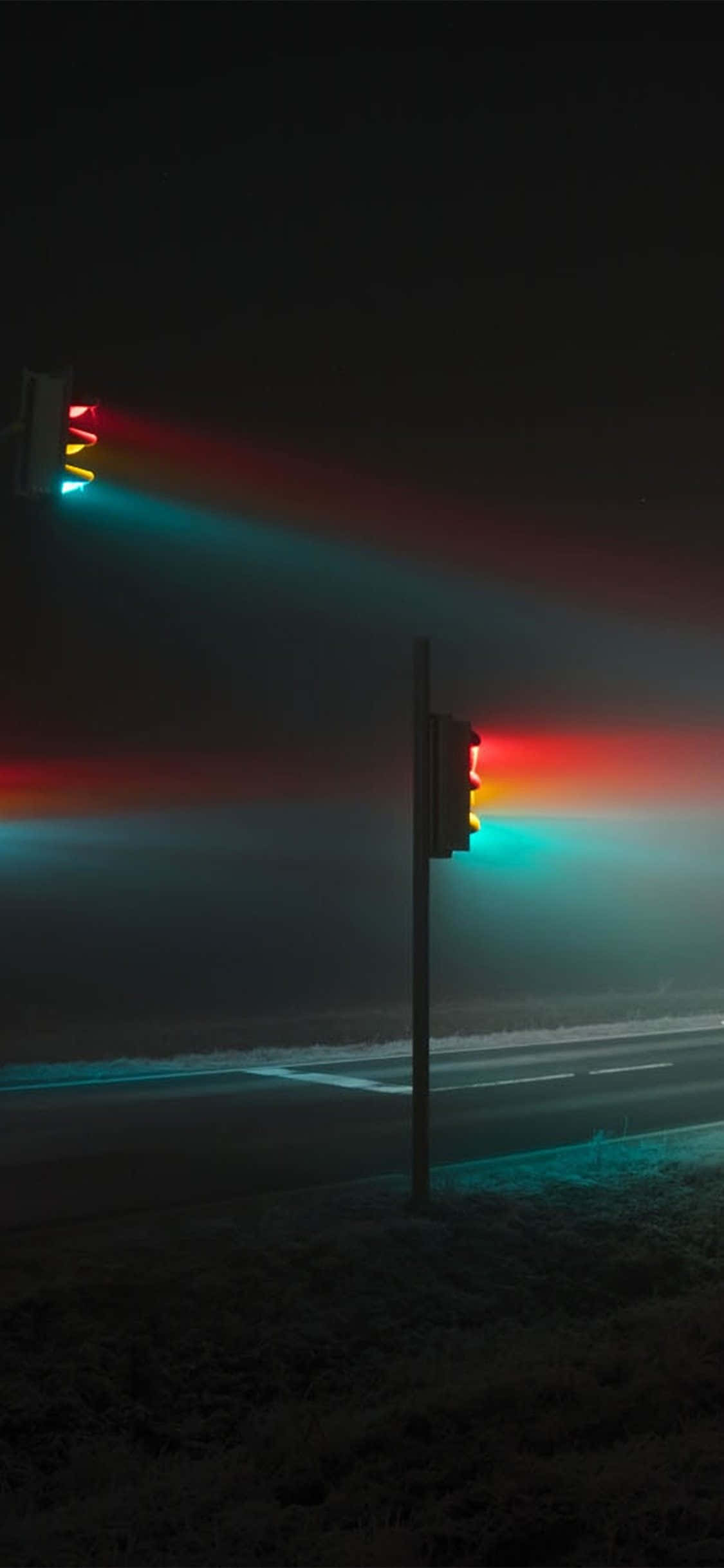 Dark Crossroad 桌布 壁紙 — 兩個交通燈發出紅、黃、綠光，在霧濛濛的夜路上投射出鮮豔的光條。