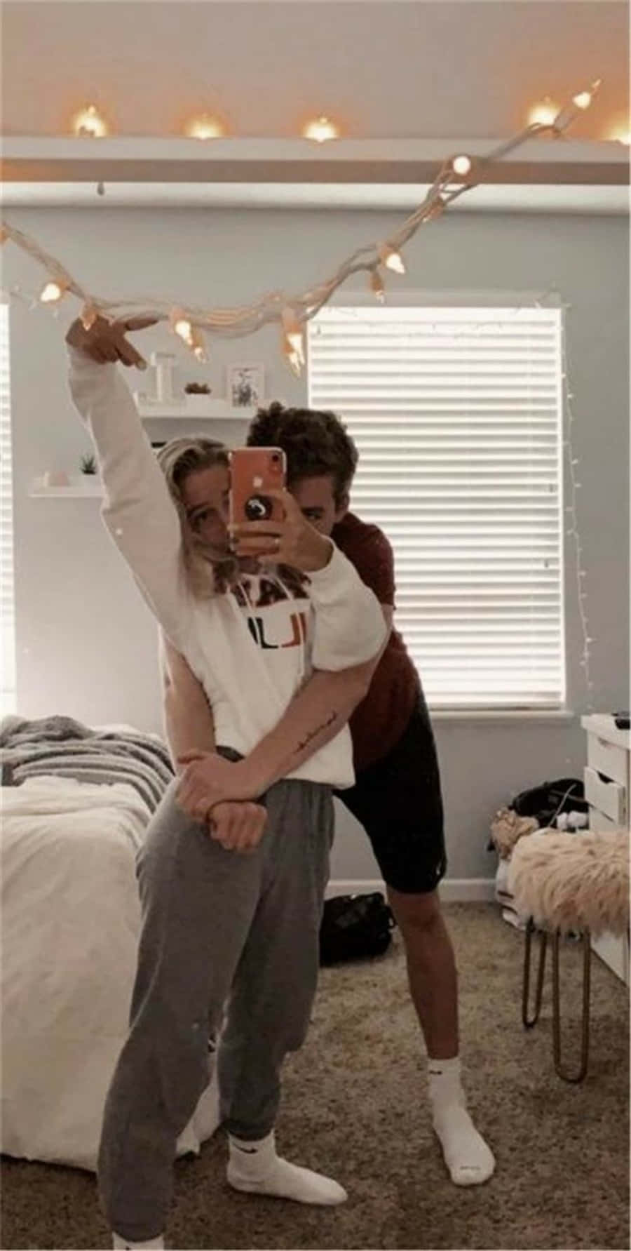 Cute Boyfriend 桌布 壁紙 — 兩個人在一個由燈串和窗簾照亮的舒適臥室裡擁抱並自拍。