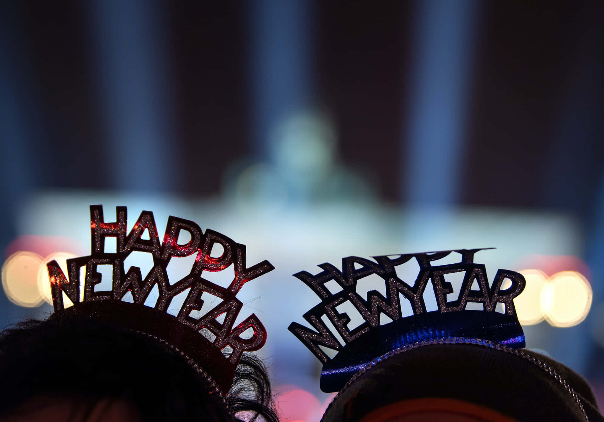 兩個人在夜間派對上戴著 'happy new year' 皇冠，燈光模糊。 — 新年動畫 壁紙
