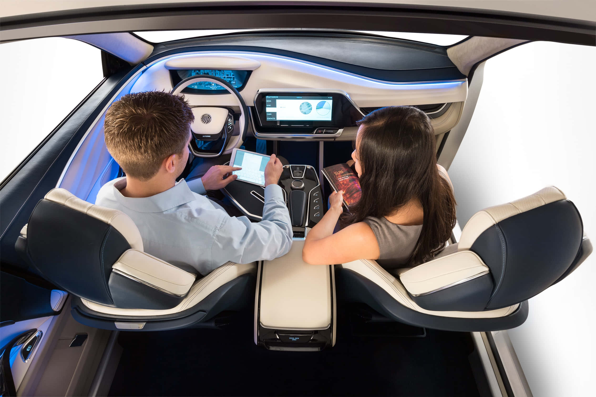Car Technology 桌布 壁紙 — 兩個人坐在未來感十足的車廂內使用平板電腦，藍色氛圍燈光突顯了流暢的儀表板和座椅。