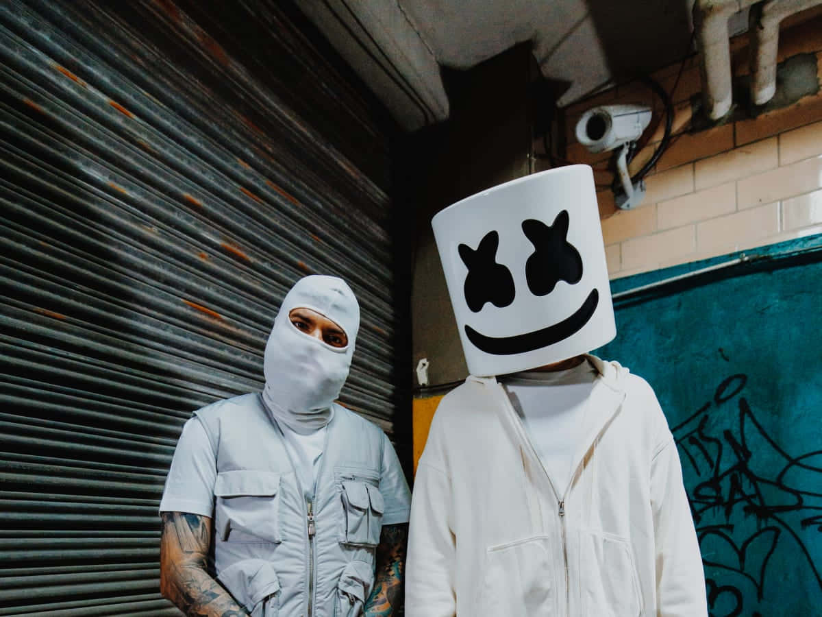 Marshmello 桌布 壁紙 — 兩個人物站在城市小巷中，一個戴著白色巴拉克拉瓦頭套，另一個戴著標誌性的棉花糖頭盔，有黑色眼睛和微笑。
