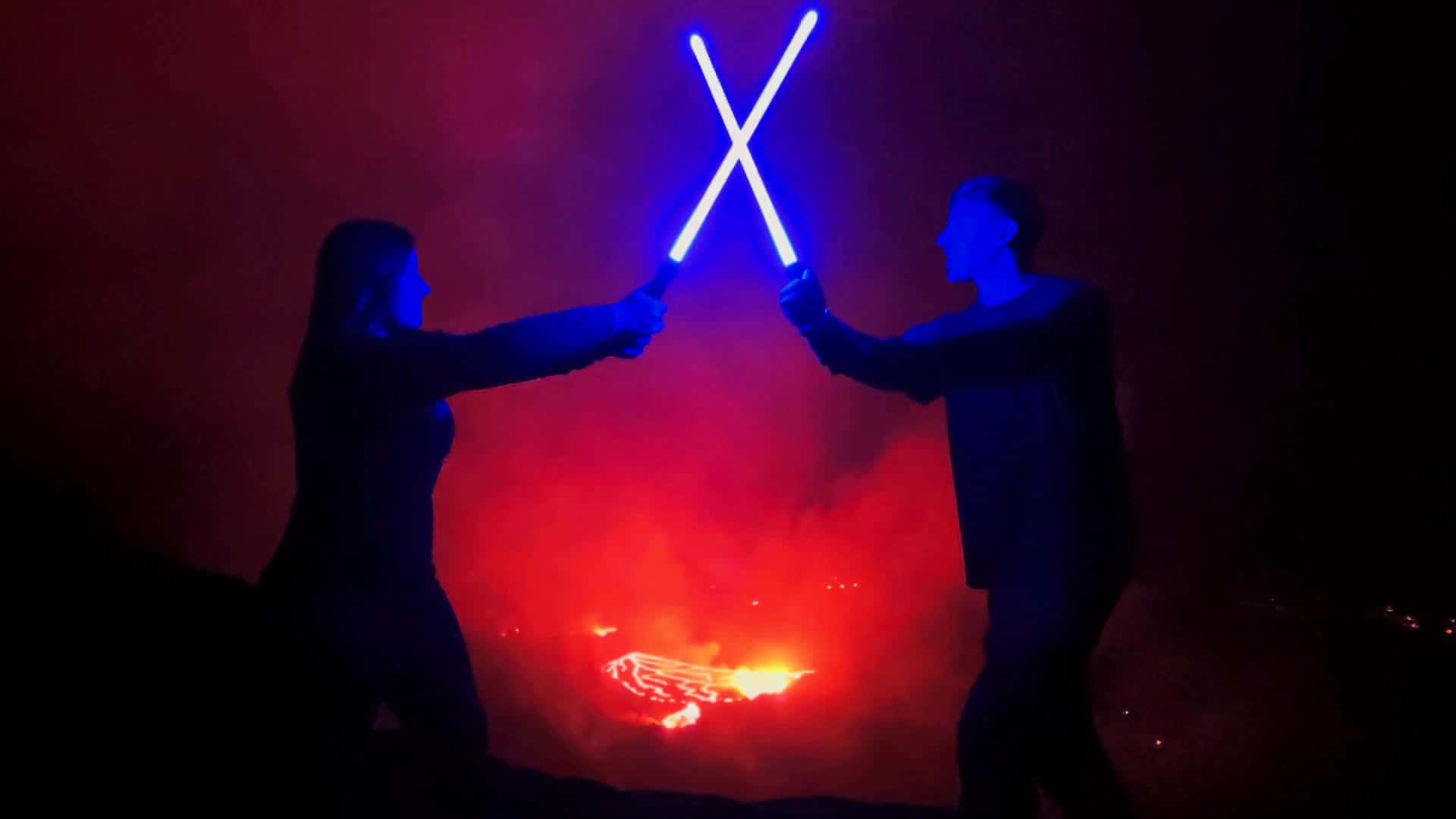Lightsaber Duels 桌布 壁紙 — 兩個剪影人物在夜間以發光的藍色光劍決鬥，背景是火紅和橙色的煙霧。