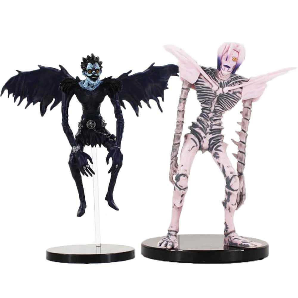Death Note Rem 桌布 壁紙 — 兩個動漫風格的有翼骷髏生物人偶，一個黑色有蝙蝠翅膀，另一個粉紅色有骷髏翅膀，站在黑色底座上。
