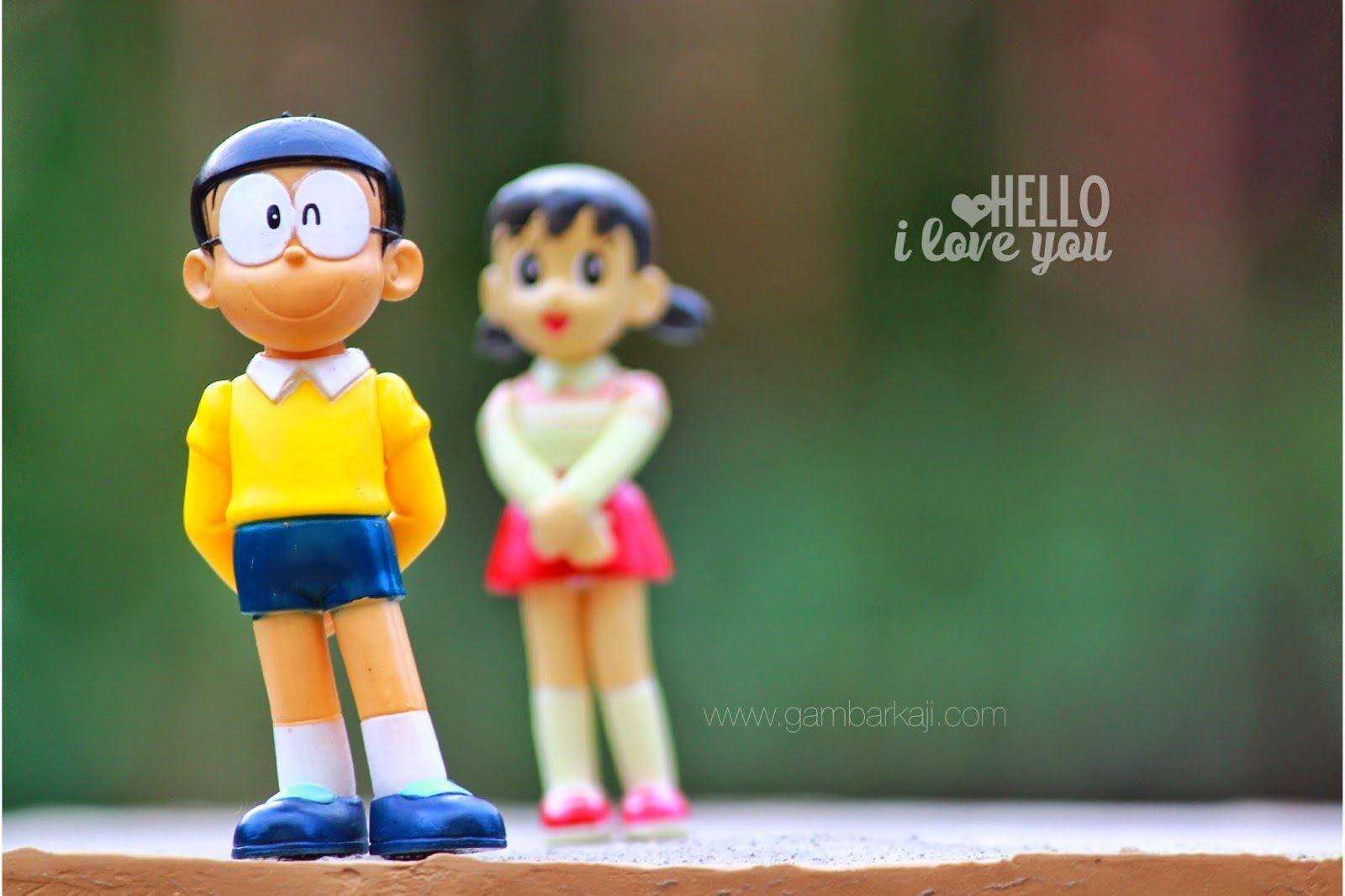 Doraemon 桌布 壁紙 — 兩個塑膠動漫公仔多啦A夢和靜香並排站在一個模糊綠色背景的窗台上。