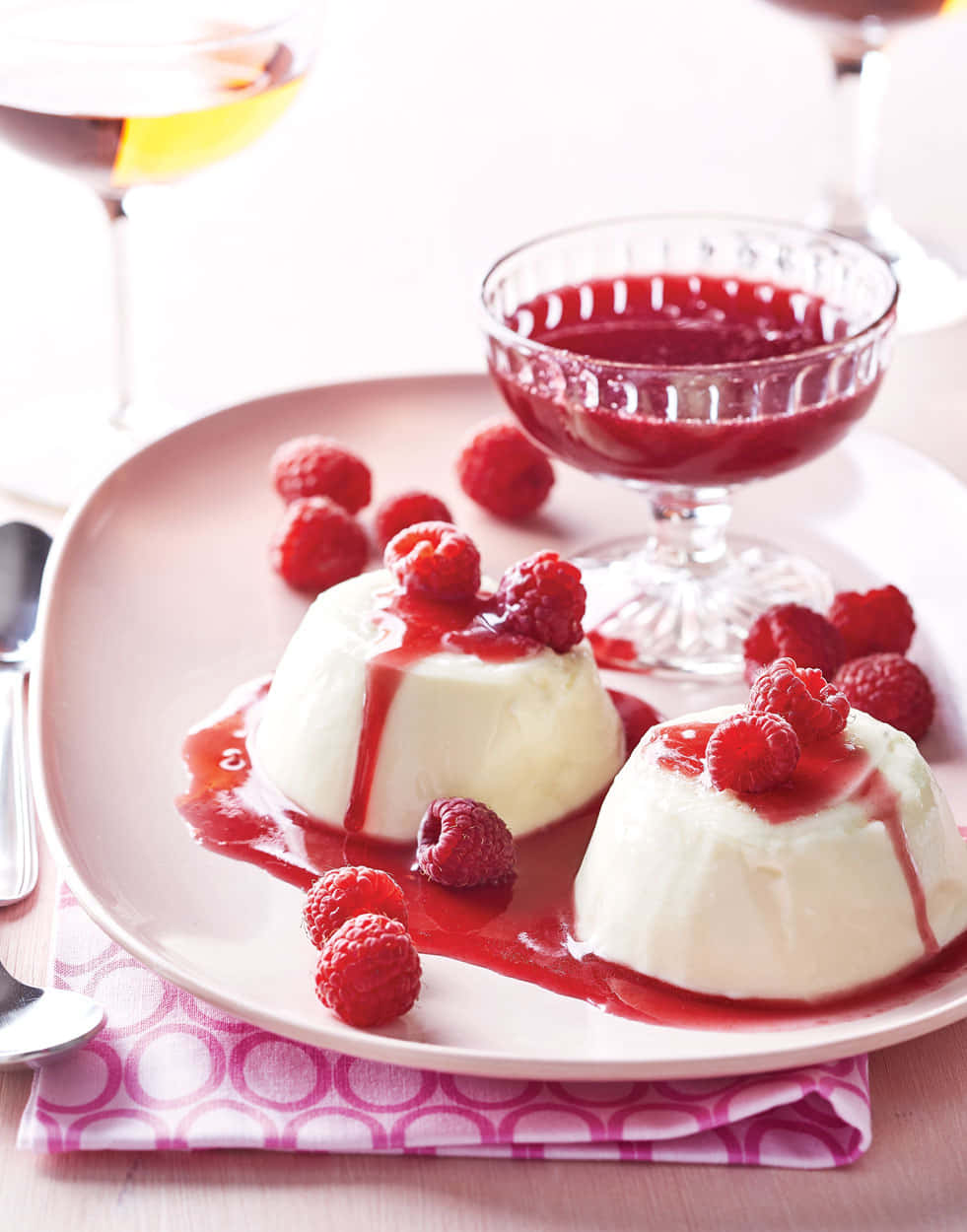 Blancmange 桌布 壁紙 — 兩個奶油白色意式奶凍甜品，上面放上新鮮紅桑子，並淋上鮮紅色紅桑子醬，放在粉紅色碟上。