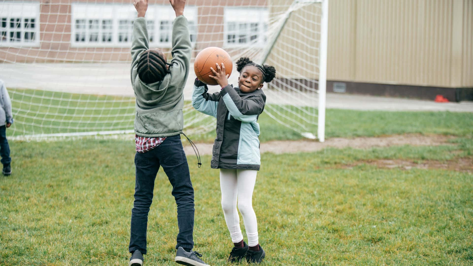 Best Sports 桌布 壁紙 — 兩個孩子在草地上打籃球，身後有一個足球龍門。