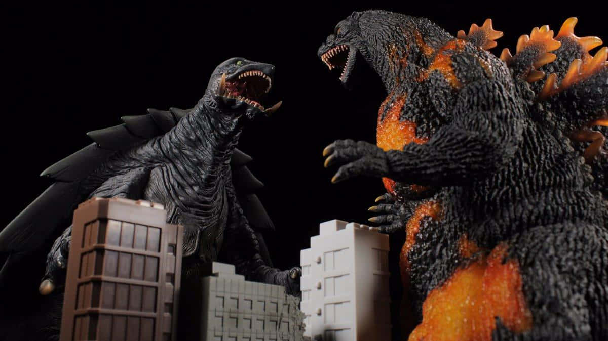 Burning Godzilla 桌布 壁紙 — 兩個巨型怪獸模型哥斯拉和王者基多拉在黑色背景下的微型城市建築中互相咆哮。
