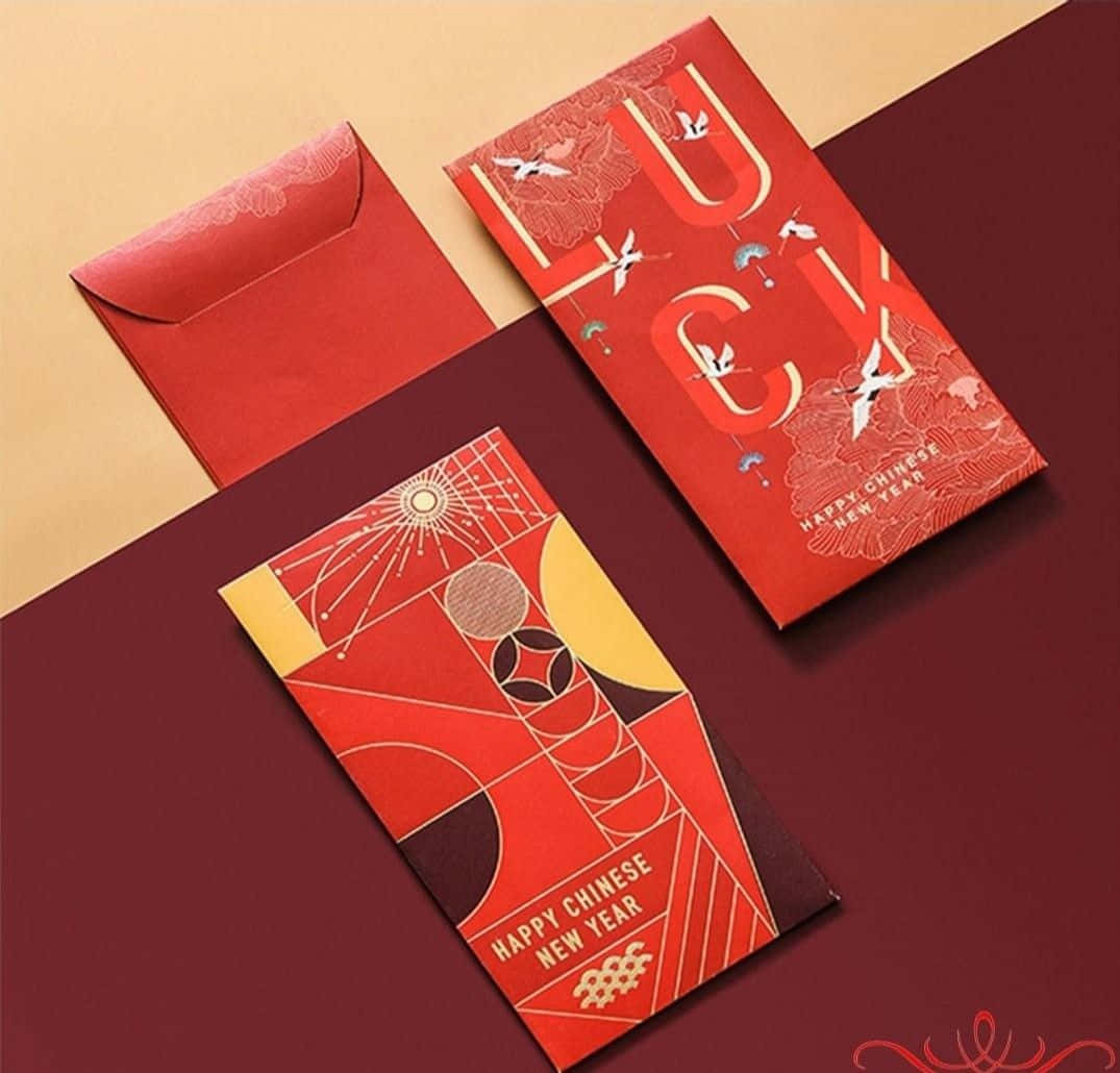 Red Envelope 桌布 壁紙 — 兩個帶有幾何和鳥類圖案的紅色中國新年利是封，放在栗色和米色的表面上。