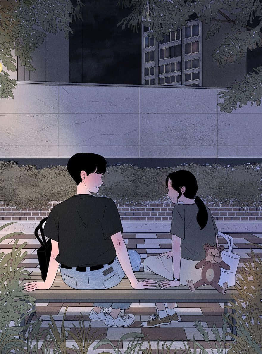 Cute Anime Couple 桌布 壁紙 — 兩個年輕人夜晚並排坐在長椅上，周圍是樹葉和城市建築，在昏暗燈光下分享寧靜的親密時光。