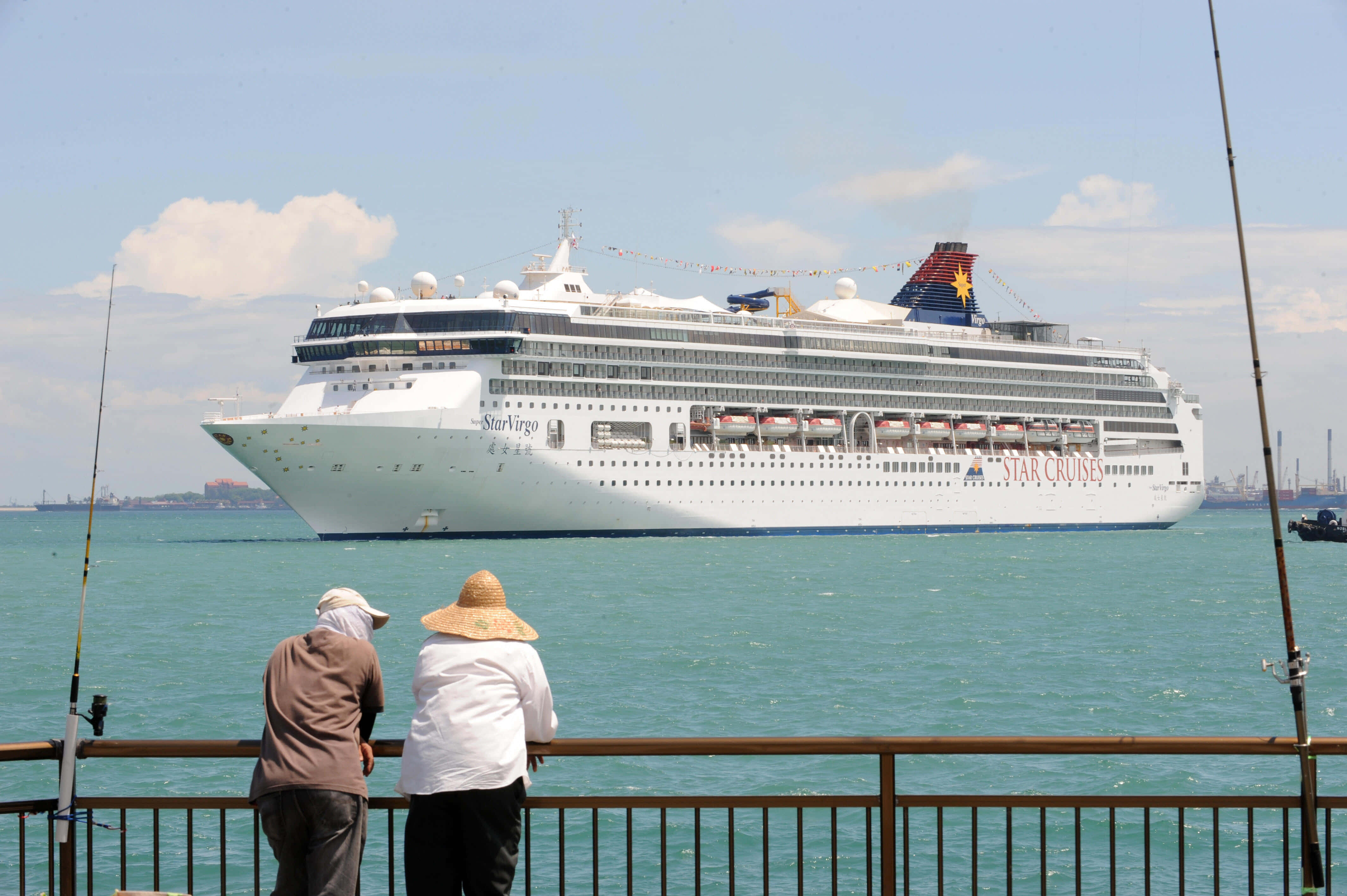 Cruise Ship 桌布 壁紙 — 兩個戴帽的人看着一艘巨大的白色星夢郵輪在部分多雲的天空下在碧綠的水面上滑行而過。