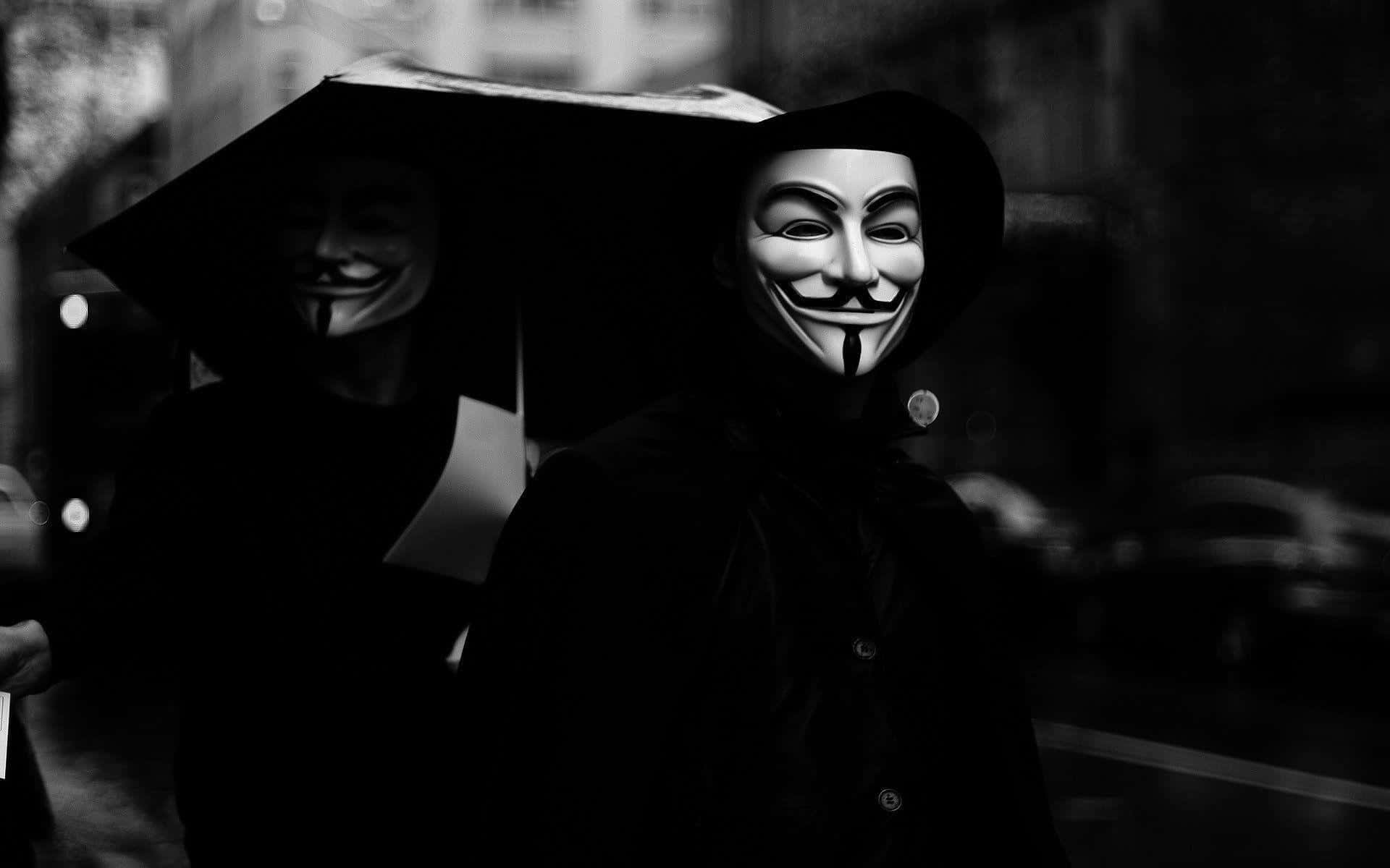 Anonymous 桌布 壁紙 — 兩個戴著標誌性蓋伊·福克斯面具的人物在雨夜的城市街道上撐著傘，以黑白呈現。