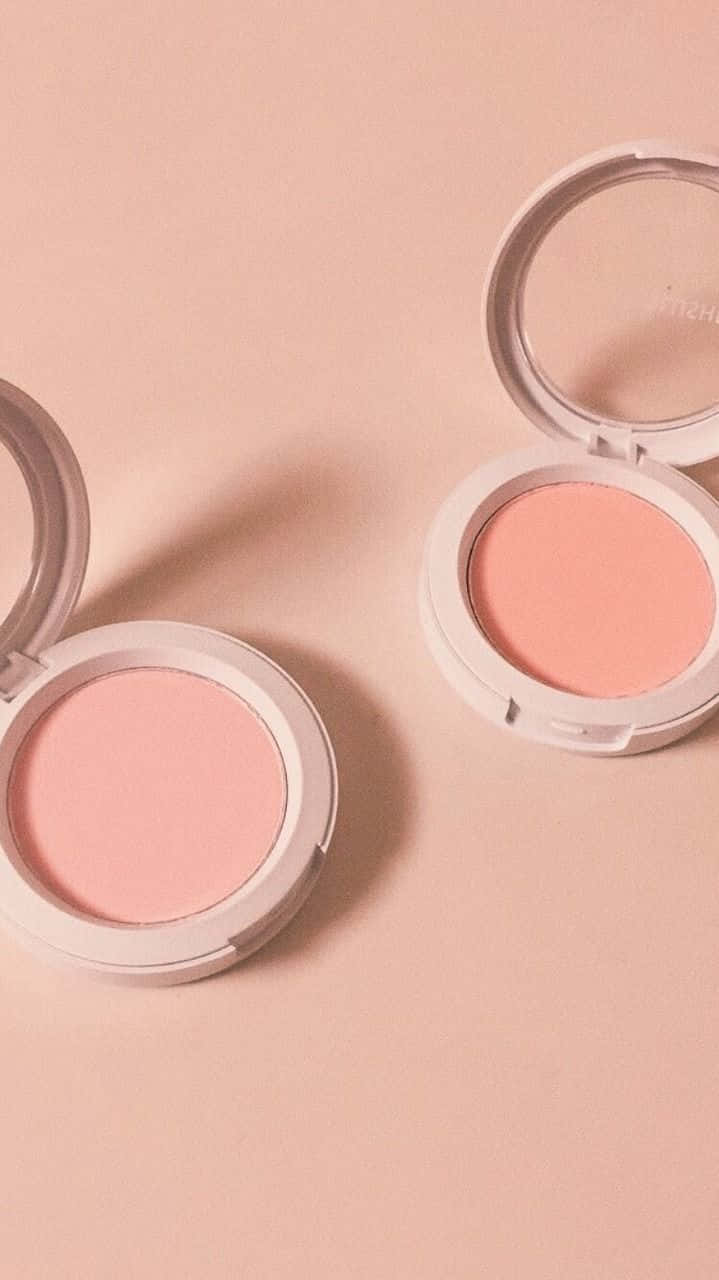 Cosmetic 桌布 壁紙 — 兩個打開的胭脂粉盒，內含柔軟的粉紅色和蜜桃色粉末，放置在相配的淡粉紅色表面上。
