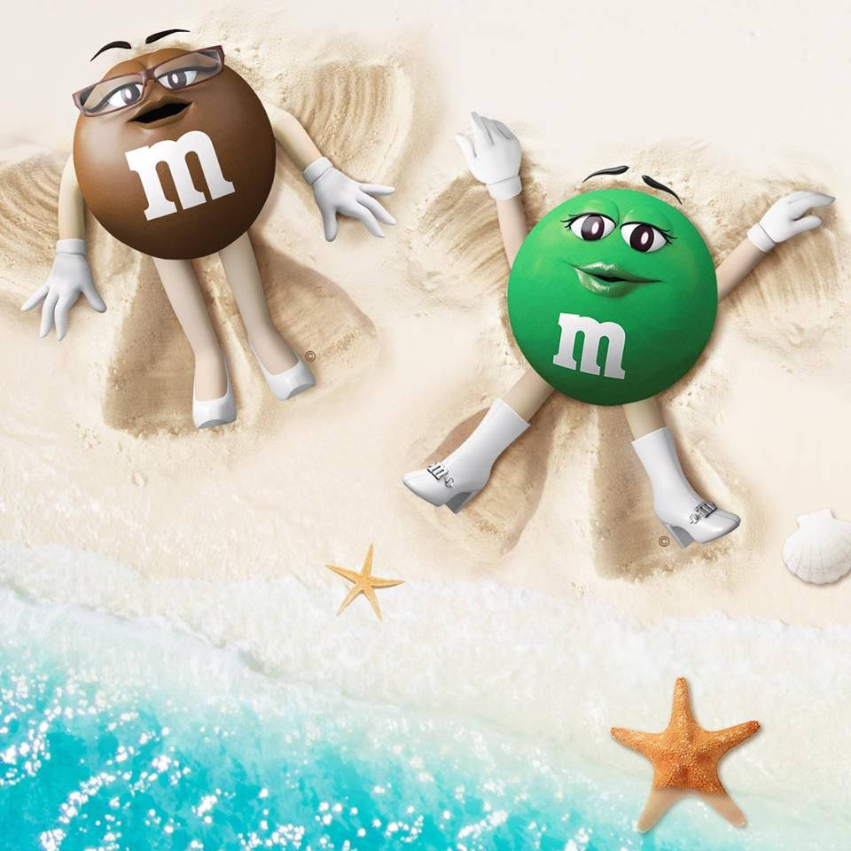 Chocolate 桌布 壁紙 — 兩個擬人化的M&M角色在沙灘上休憩，附近有藍綠色的海浪和海星。