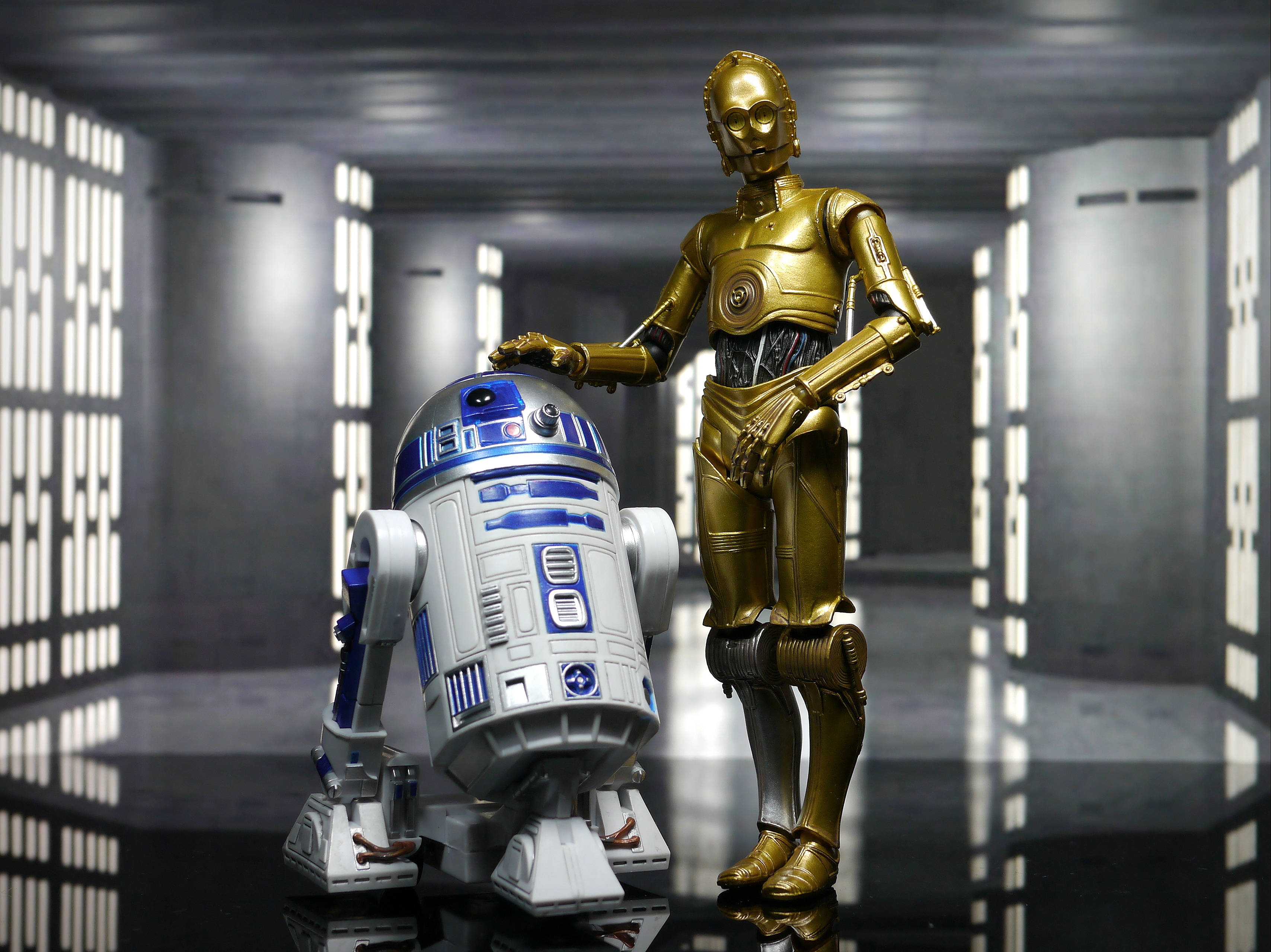 機械人 桌布 壁紙 — 兩個標誌性的星戰機械人R2D2和C3PO站在一個時尚的未來主義走廊中，帶有發光面板和反射地板。
