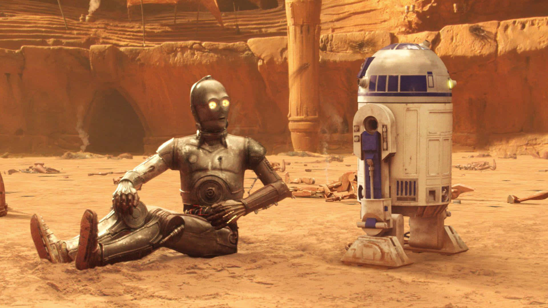 C-3po 桌布 壁紙 — 兩個機械人C-3PO和R2-D2坐在一個佈滿灰塵的沙漠峽谷中，周圍有橙色岩石結構和散落的碎片。