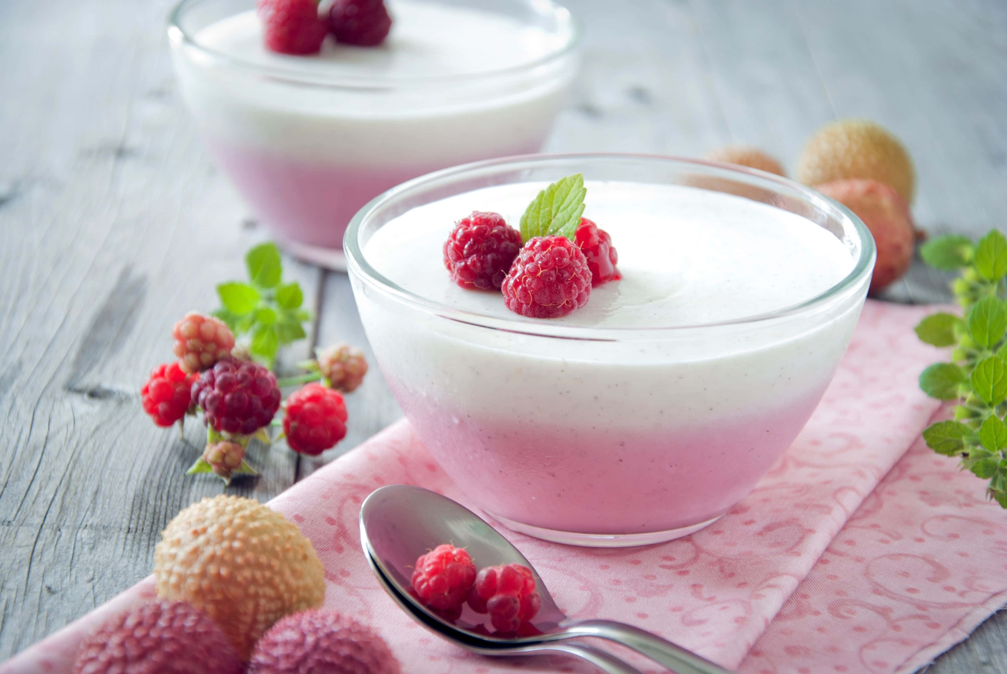 Spring Desserts 桌布 壁紙 — 兩個玻璃碗盛載粉紅和白色分層乳酪，上面放上新鮮覆盆子和薄荷，置於鄉村風木桌上。