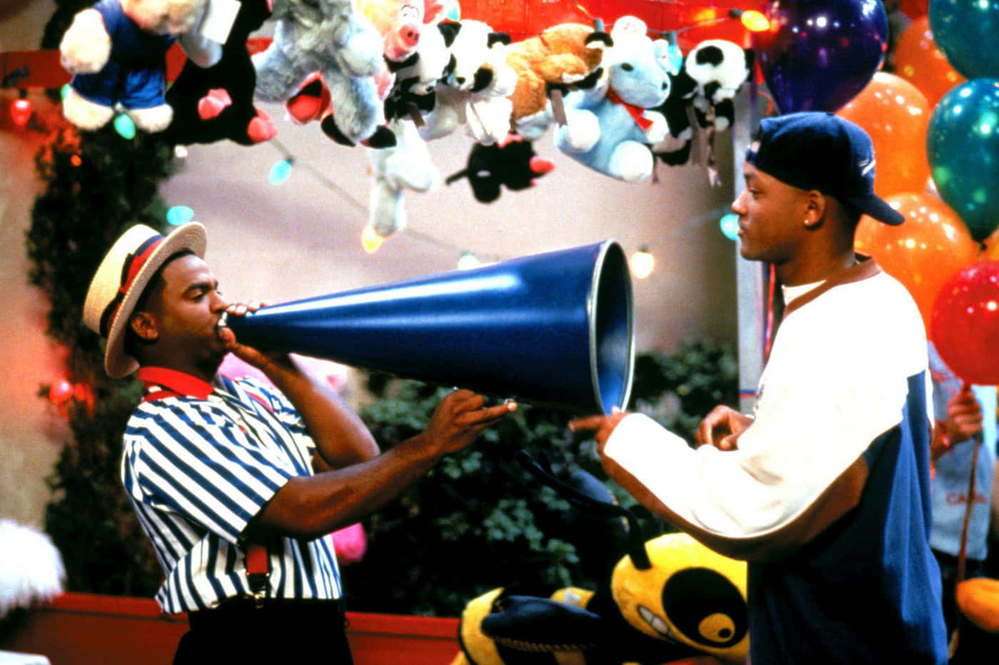 fresh prince 桌布 壁紙 — 兩個男人在掛滿毛公仔和彩色氣球的節日室內環境中與一個藍色擴音器互動。