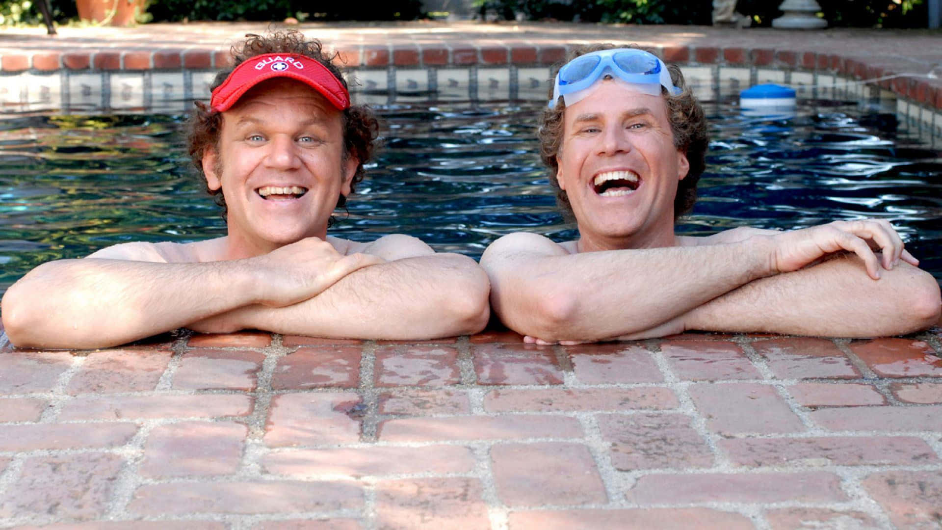 John C. Reilly 桌布 壁紙 — 兩個男人在泳池中，手臂交叉放在磚邊上，在明亮的陽光下開懷大笑。