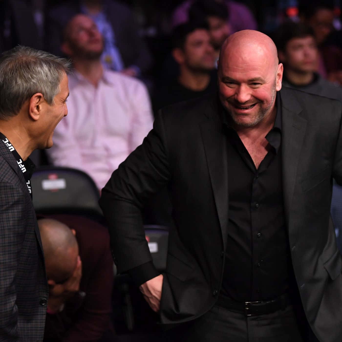 UFC 桌布 壁紙 — 兩個男人在燈光昏暗的場館中開懷大笑，背景是模糊的觀眾。