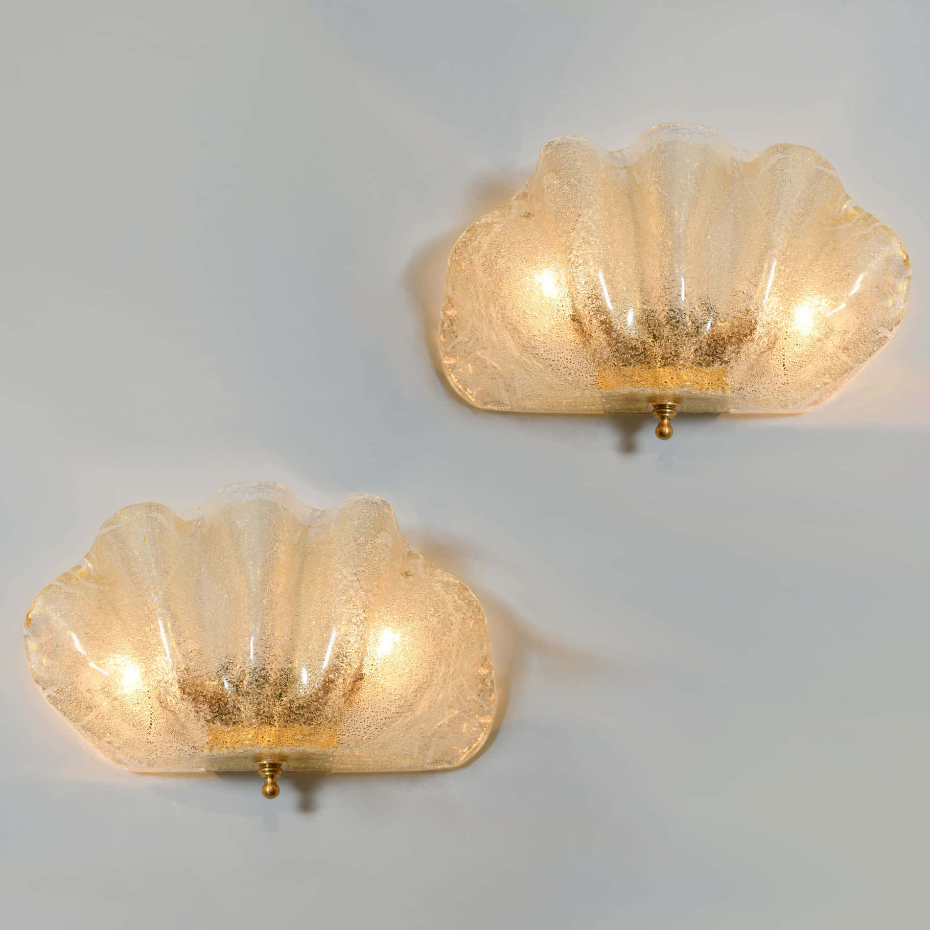 Clam Shell 桌布 壁紙 — 兩個發光的貝殼形玻璃壁燈，帶有金色斑點，向素牆投射溫暖的光線。