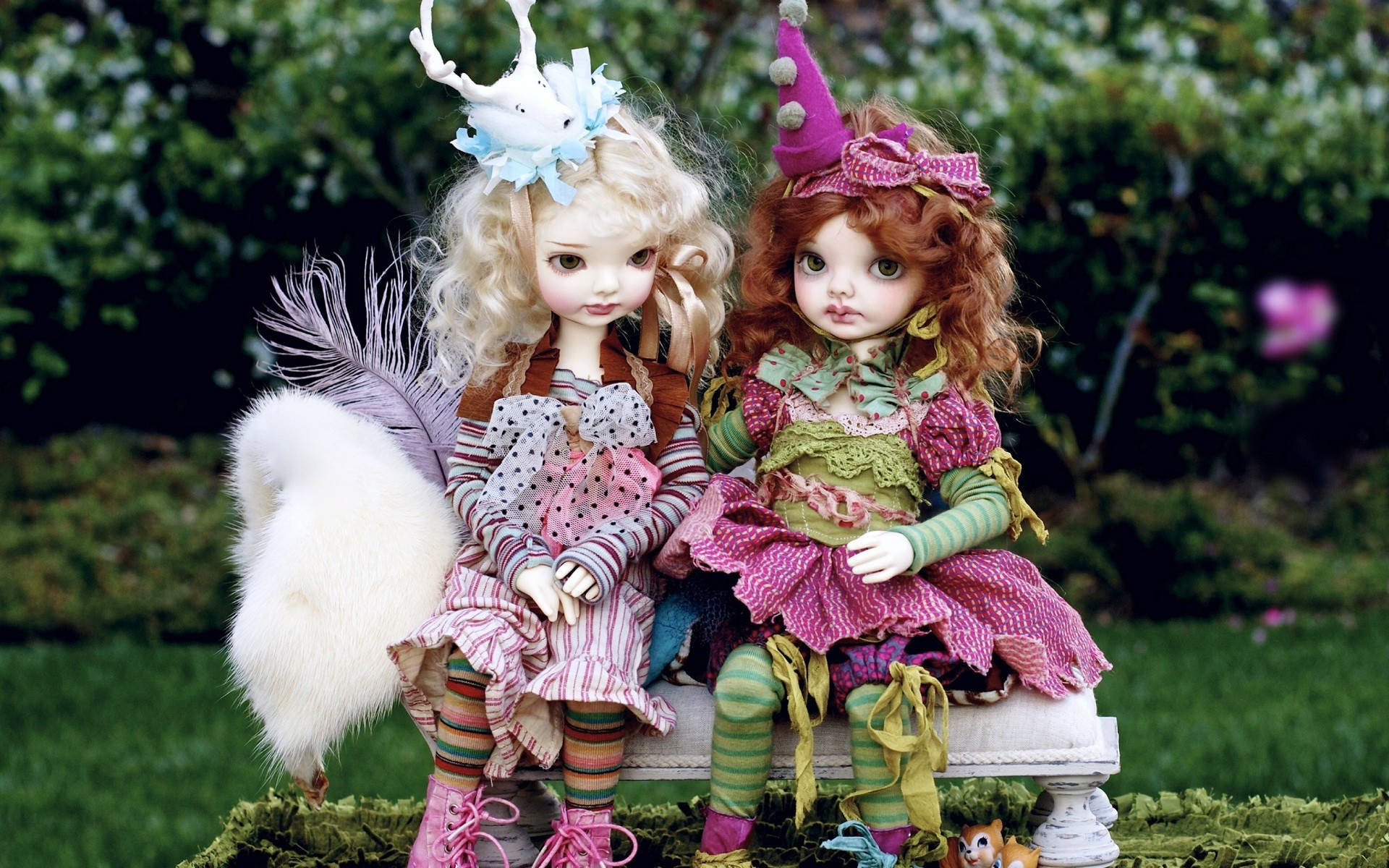 Doll 桌布 壁紙 — 兩個穿著精緻服裝和奇特頭飾的 Blythe 娃娃並排坐在花園長椅上。