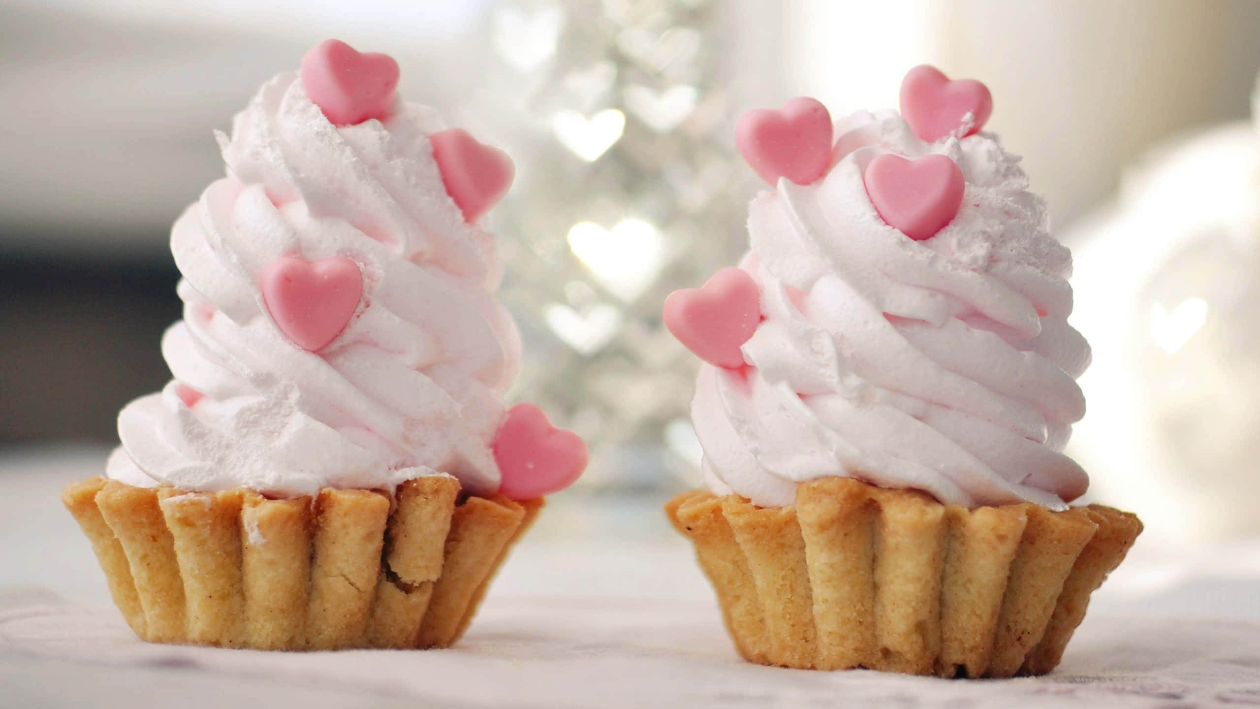 Cute Cupcake 桌布 壁紙 — 兩個精緻的心形頂部 cupcake，配上 fluffy 粉紅色糖霜，旁邊有一棵柔和模糊的心形樹。