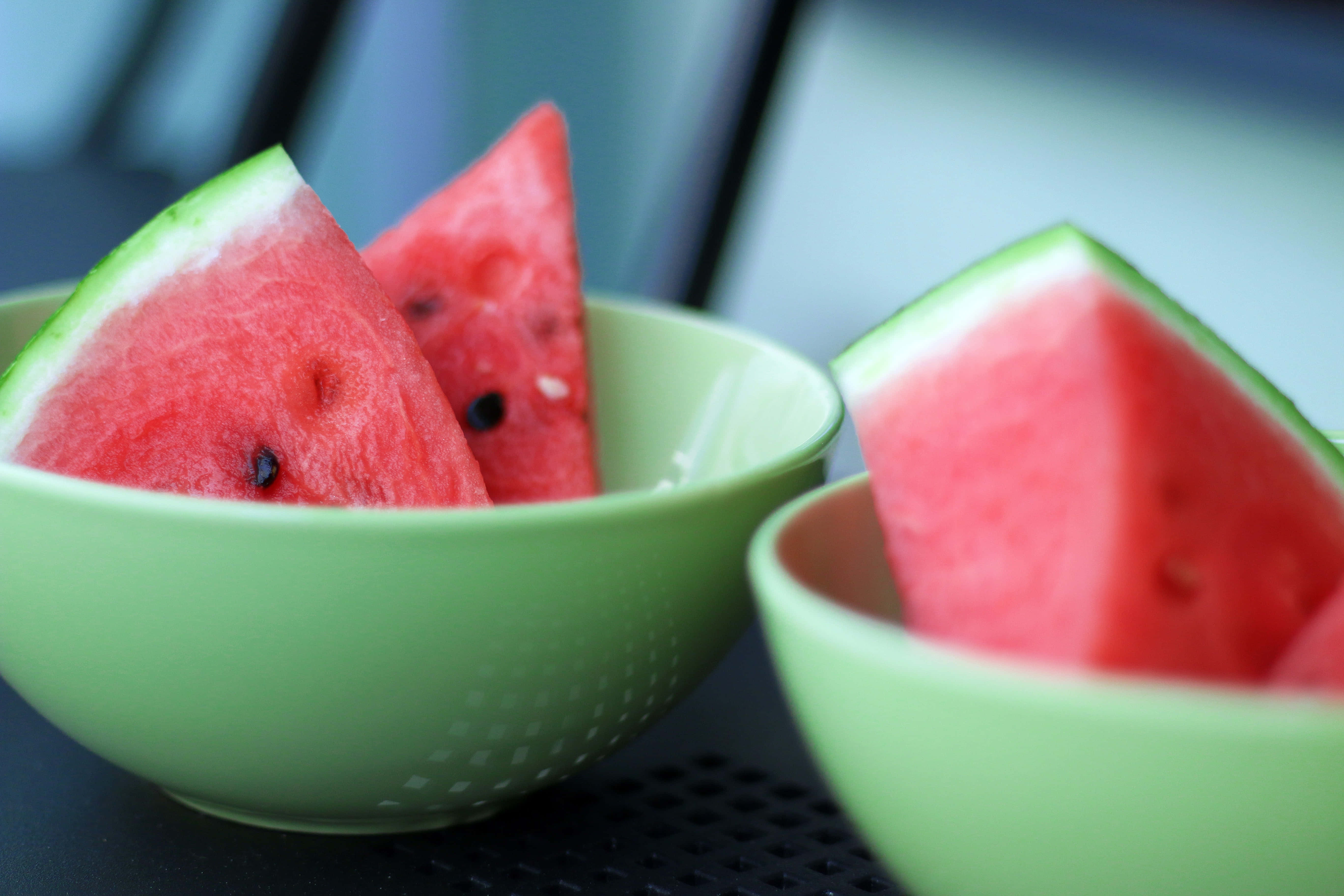 Summer Fruits 桌布 壁紙 — 兩個綠色碗盛載多汁的紅西瓜片，帶有黑色種子，背景模糊。