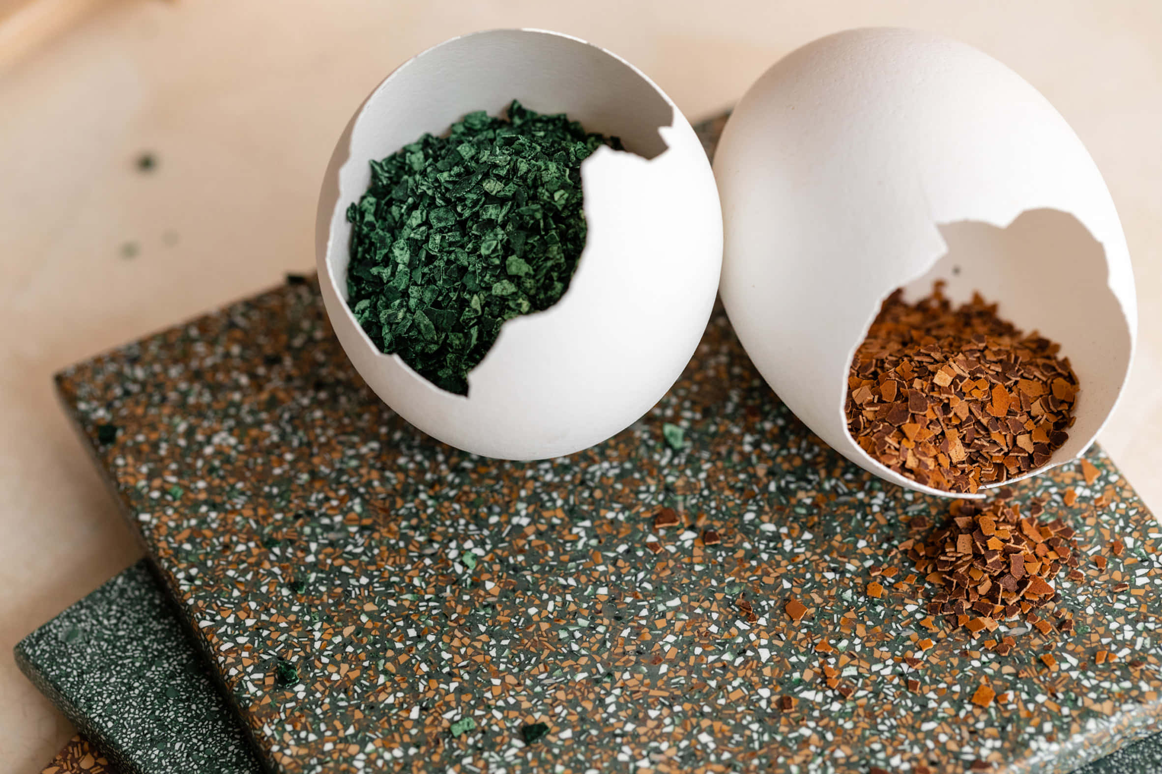 Eggshell 桌布 壁紙 — 兩個裂開嘅蛋殼喺斑點水磨石表面上裝住充滿活力嘅綠色同啡色碎香草。