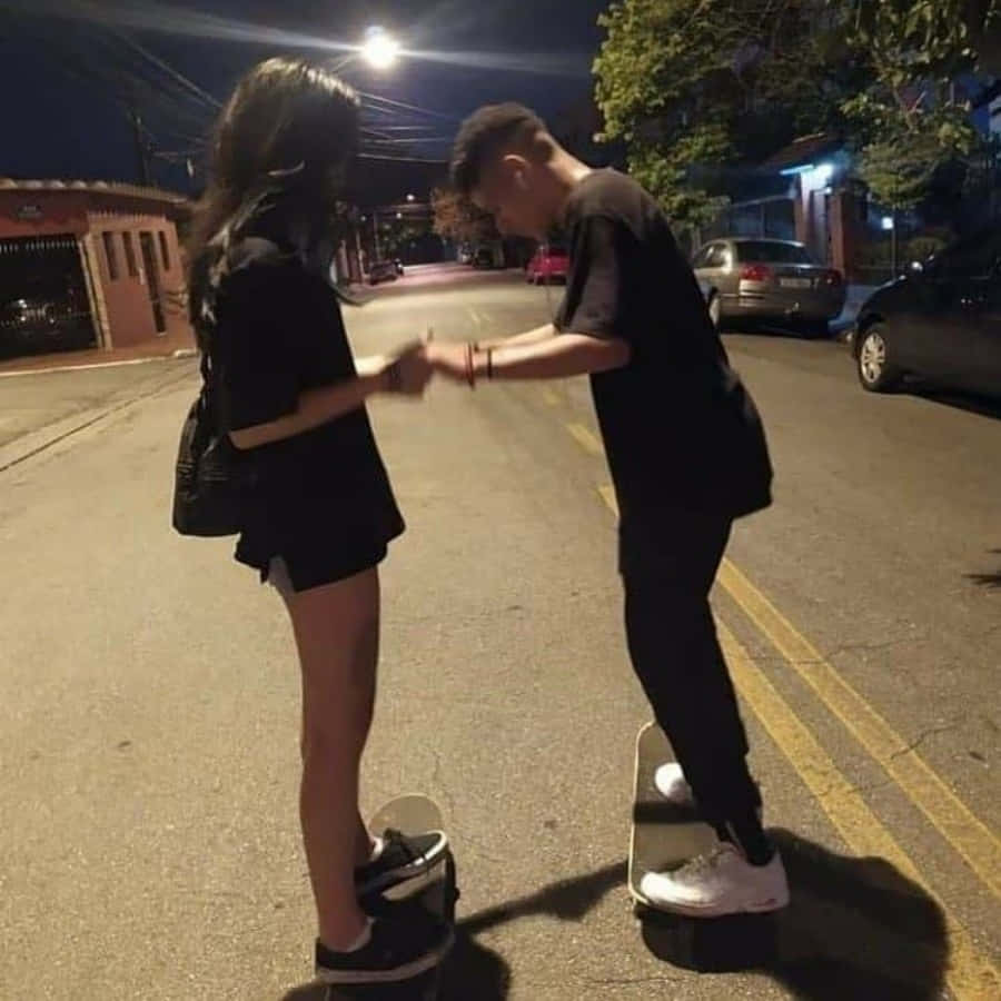 Cute Boyfriend 桌布 壁紙 — 兩個踩滑板嘅青少年喺寧靜夜晚嘅街燈下握手。
