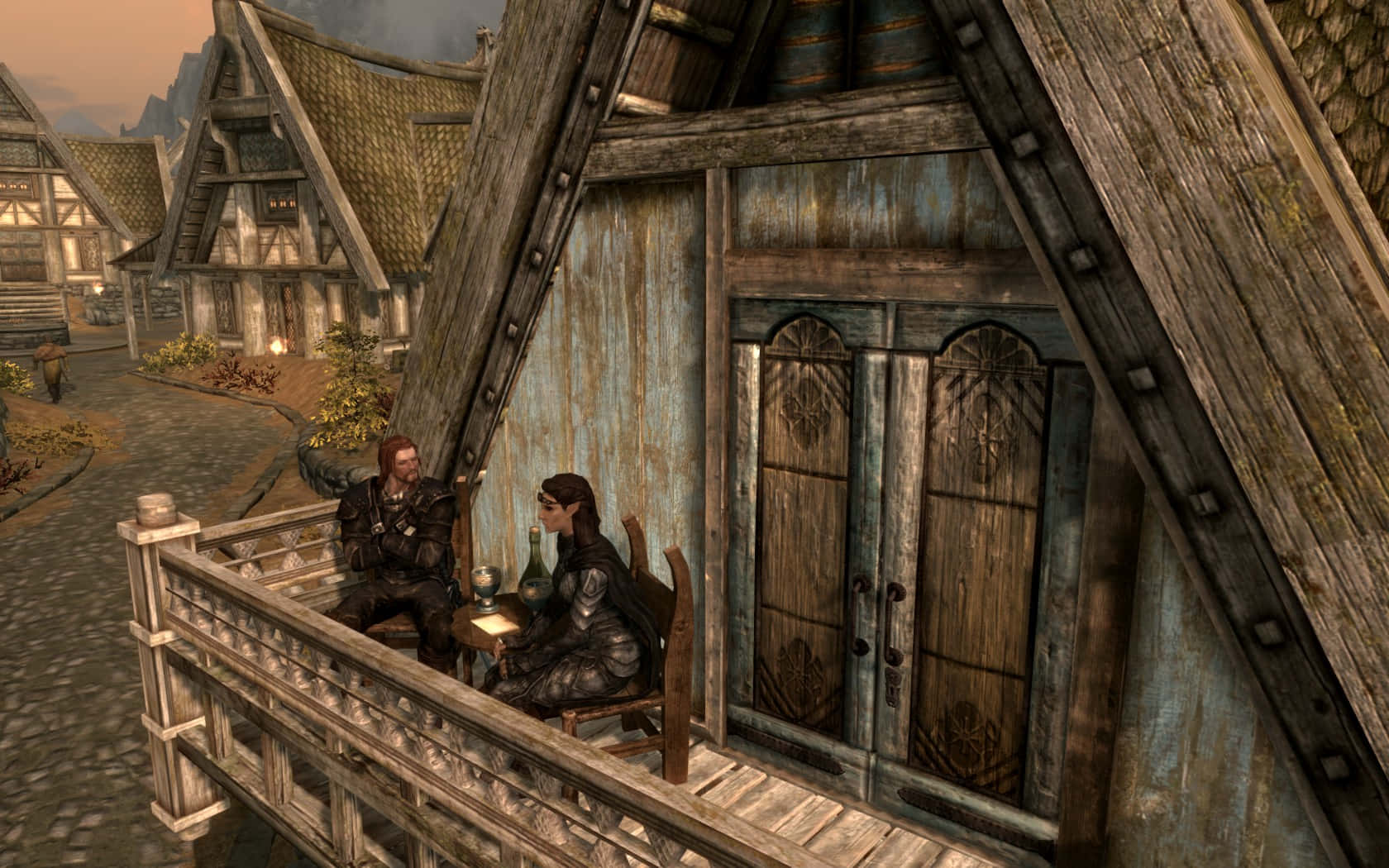 Skyrim Brynjolf 桌布 壁紙 — 兩個身穿盔甲的人物在黃昏時分坐在一間鄉村風格的中世紀酒館的木製陽台上，喝酒聊天。