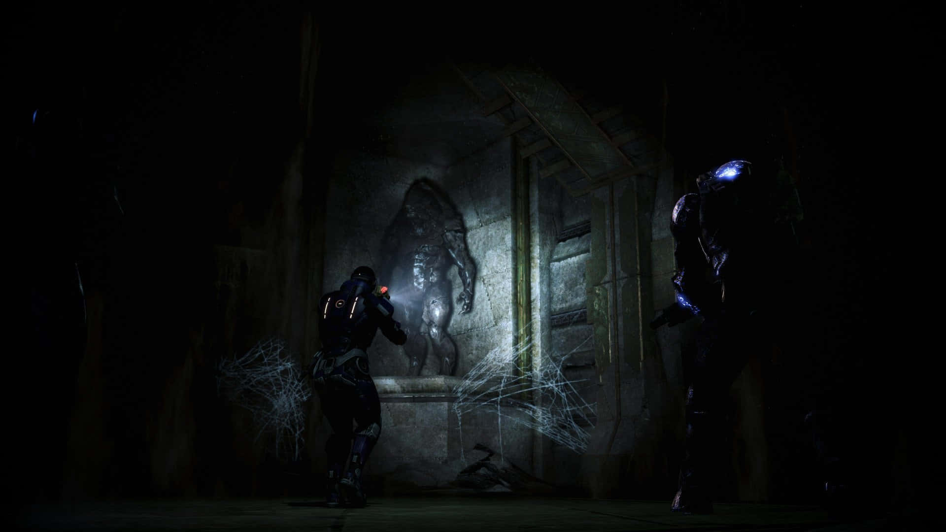 Mass Effect Legendary Edition 桌布 壁紙 — 兩個身穿盔甲的人物在黑暗廢墟中用頭燈照亮一個怪誕的石像。