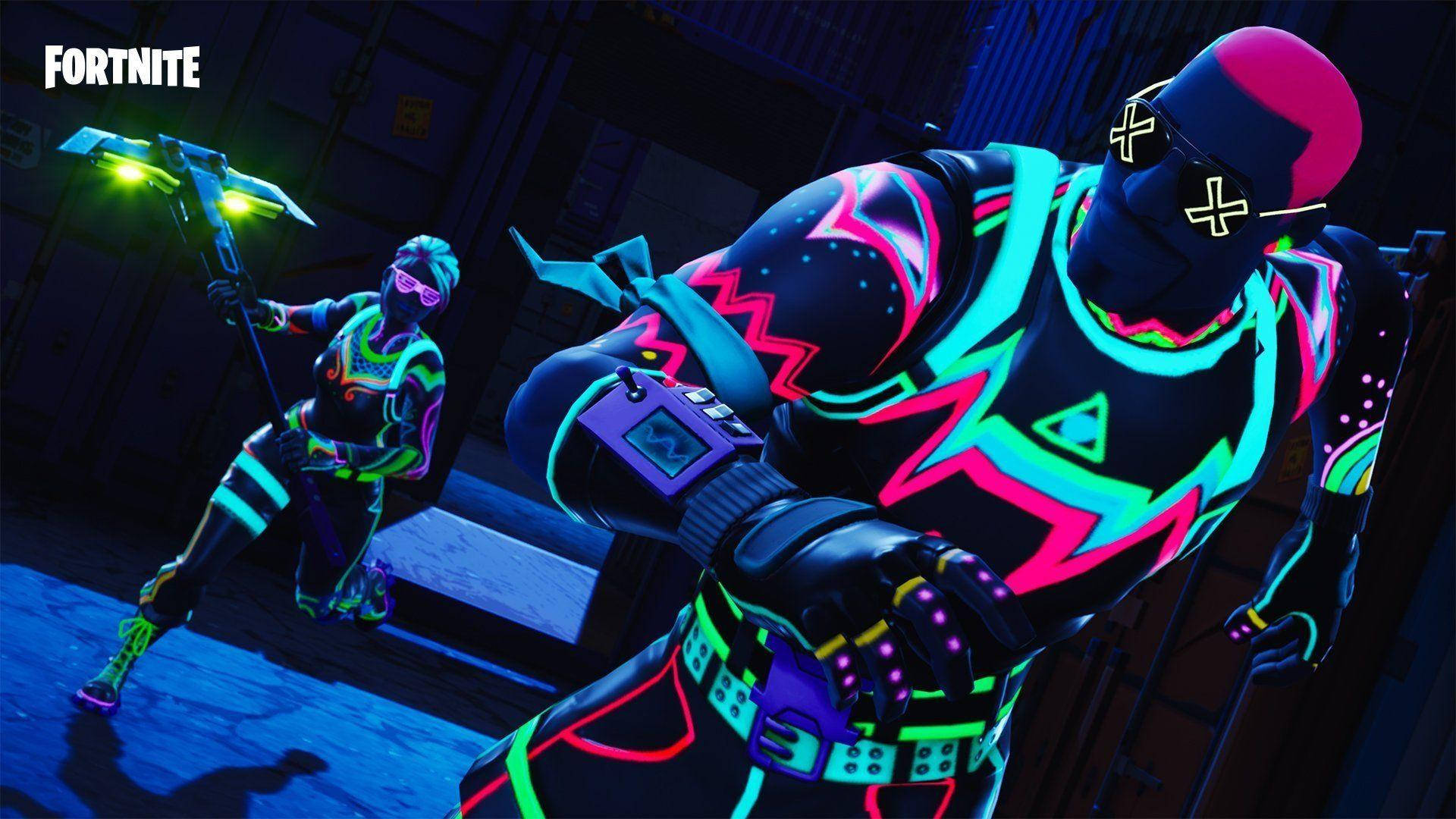 Fortnite 桌布 壁紙 — 兩個身穿霓虹發光服裝的Fortnite角色在昏暗的倉庫中手持發光武器準備就緒。