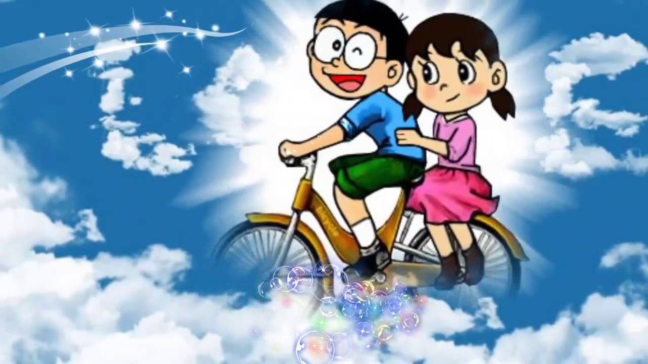Doraemon 桌布 壁紙 — 兩個開心的動畫小孩踩單車穿過 fluffy 雲朵，下面有閃爍的軌跡和彩色泡泡。