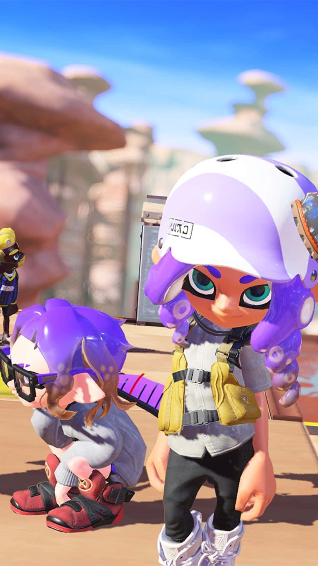 splatoon 桌布 壁紙 — 兩個風格化的紫色魷魚角色穿著遊戲裝備，站在陽光明媚的沙漠峽谷中，周圍有岩石 formations。